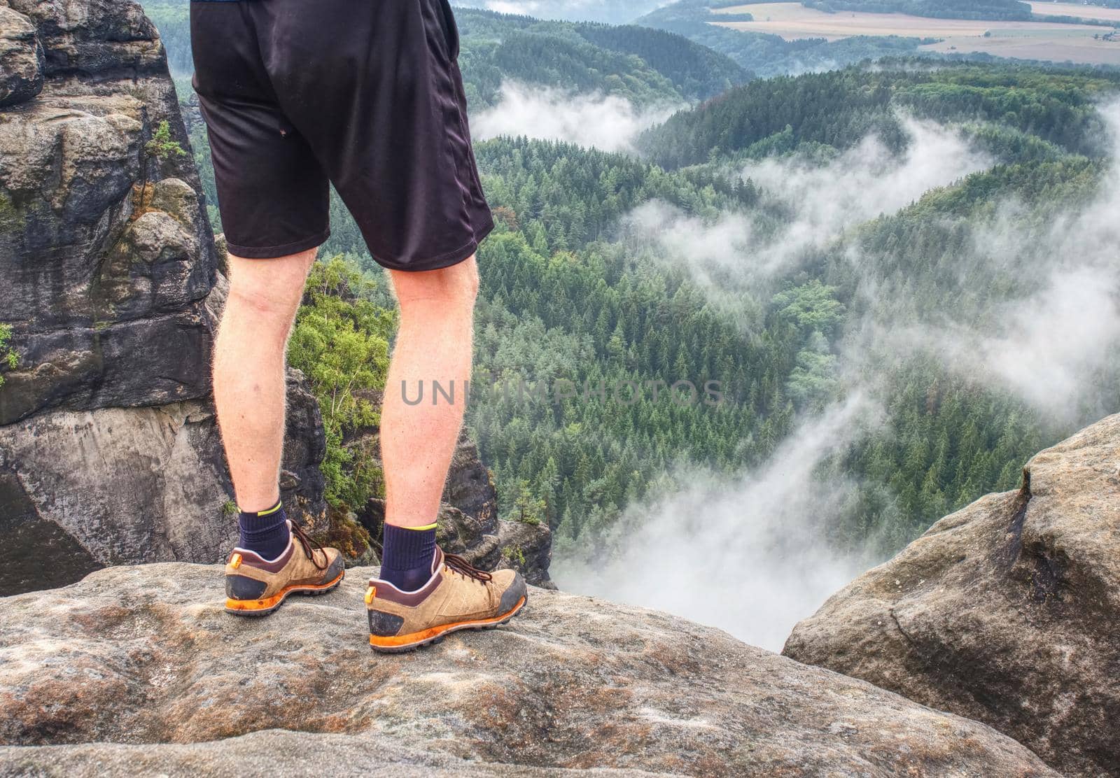 Naked legs of successful hiker on exposed sandstone rock or big stone.