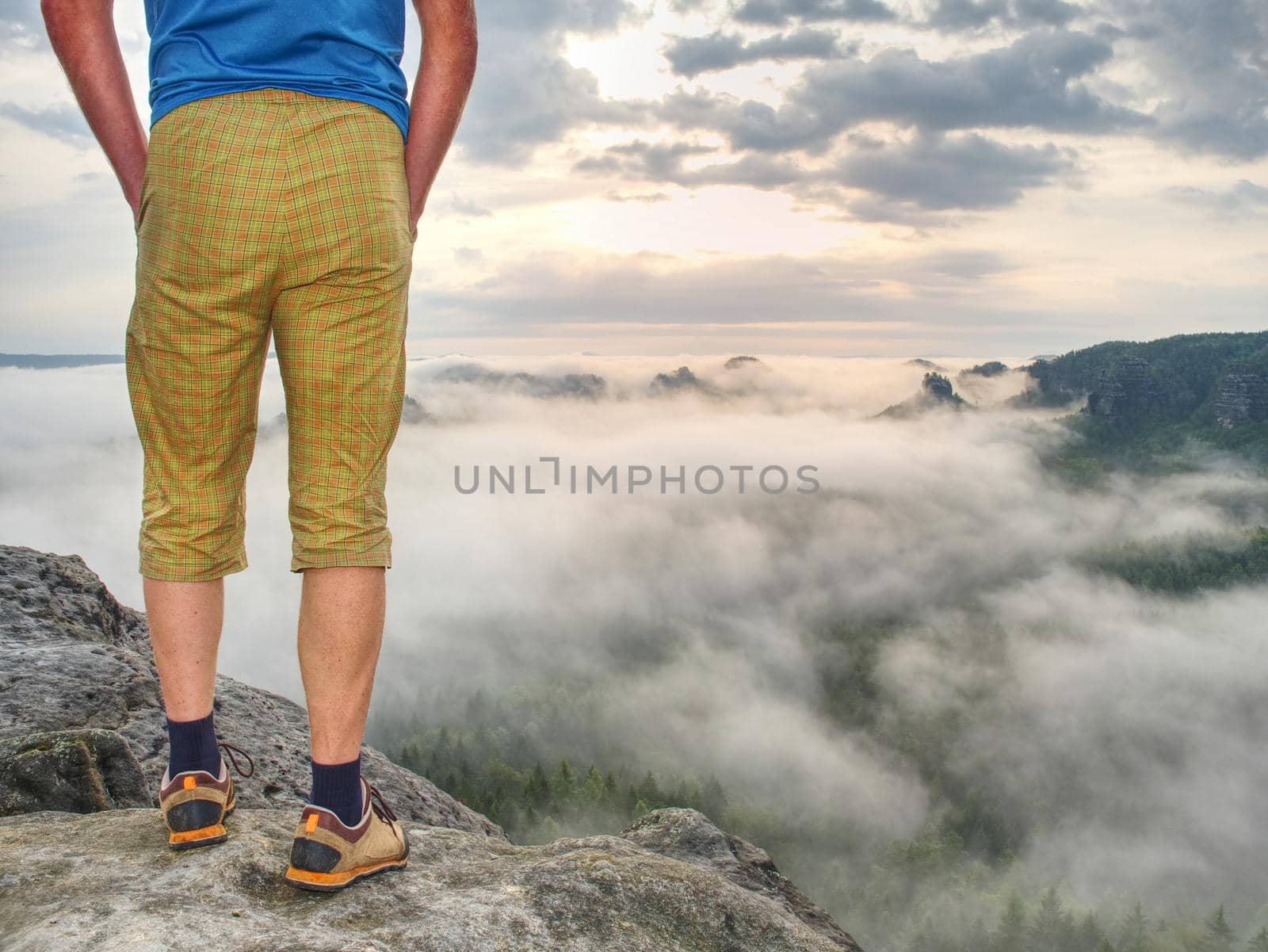 Nature misty show. Guy standing on top of the mountain. A hiking trip in rocks and  forest. Beautiful wild nature.