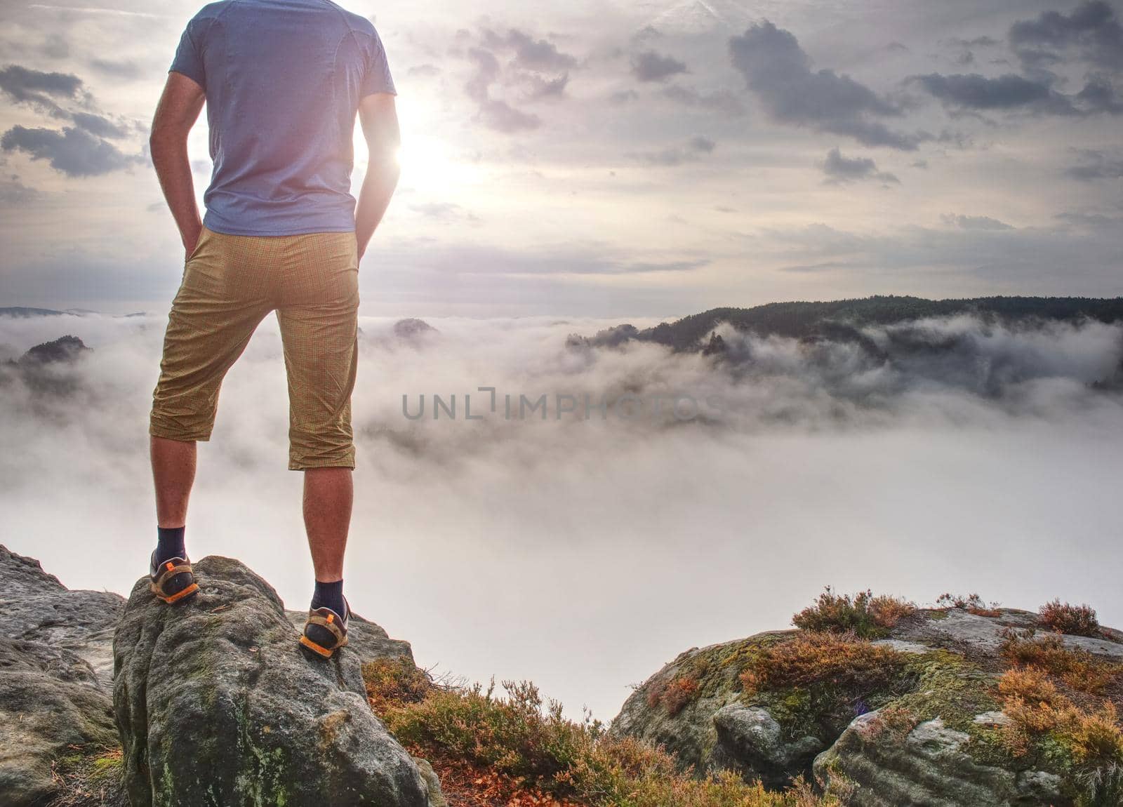 Gloomy nostalgic view into fall nature with lonely melancholic adult man. Sportsman without  jacket standing on the top  in misty morning and thinking 