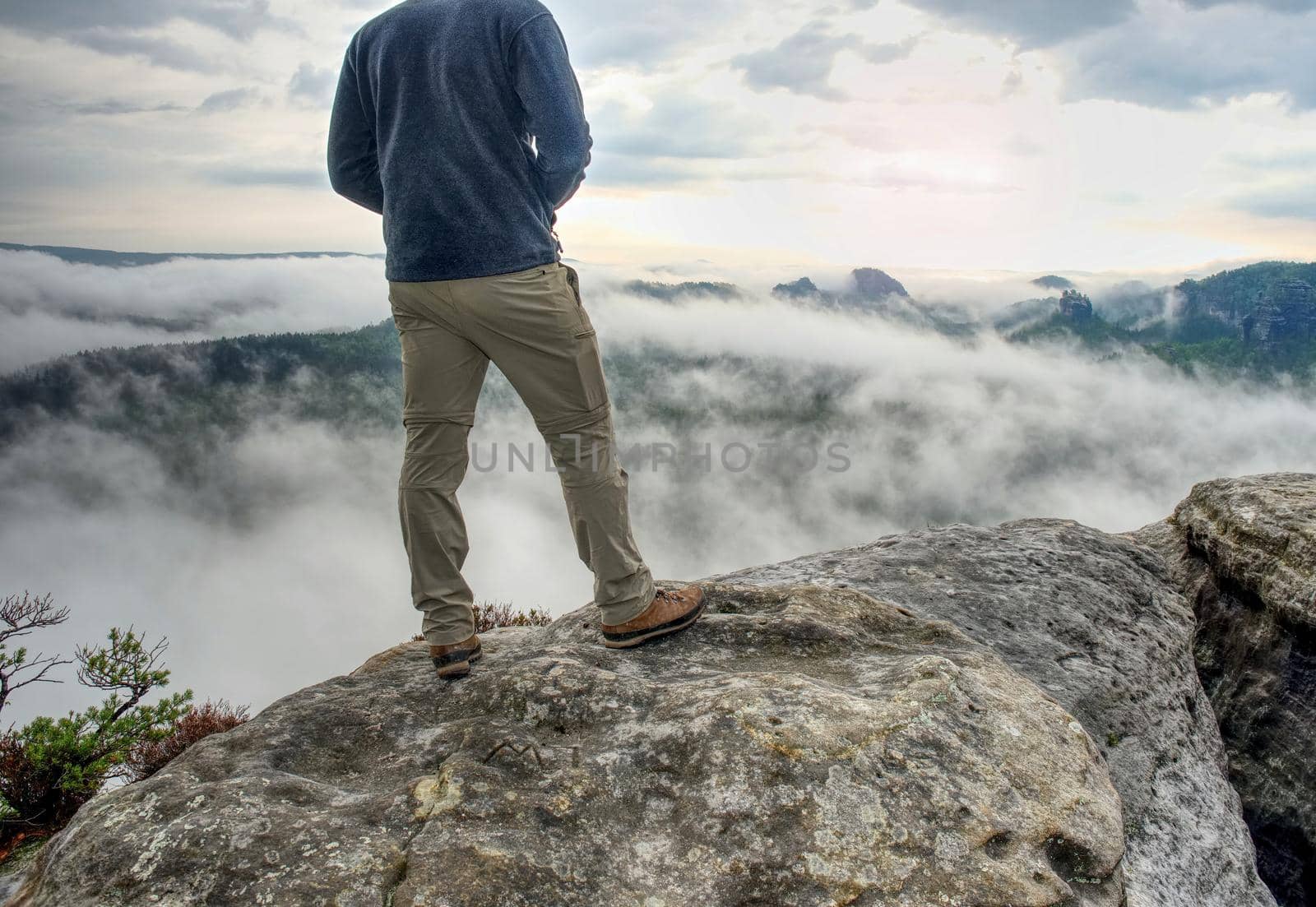 Fall nature photographer prepare camera to takes impressive photos of misty fall mountains. Tourist photographer at sharp rocky edge