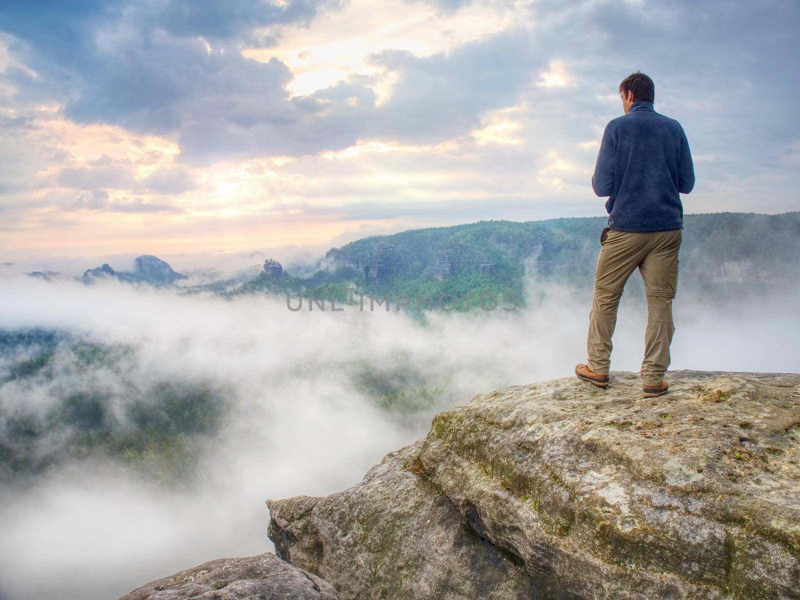 Photographer on mountain cliff looking into mist. Hiker will take picture by rdonar2