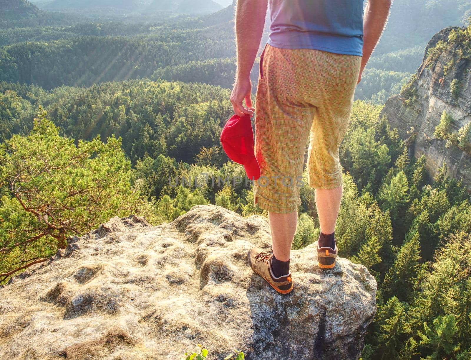 Hiker stays on a rocky ridge and enjoy view over long valley to horizon