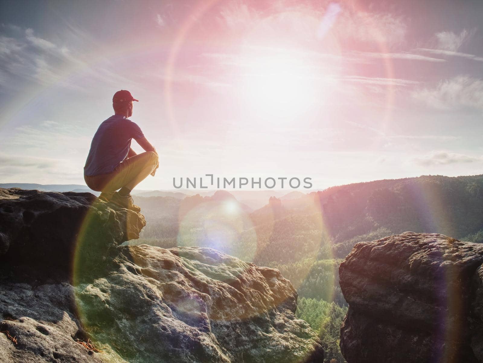 Man sitting on the rock cliff in mountain and watching sunrise by rdonar2