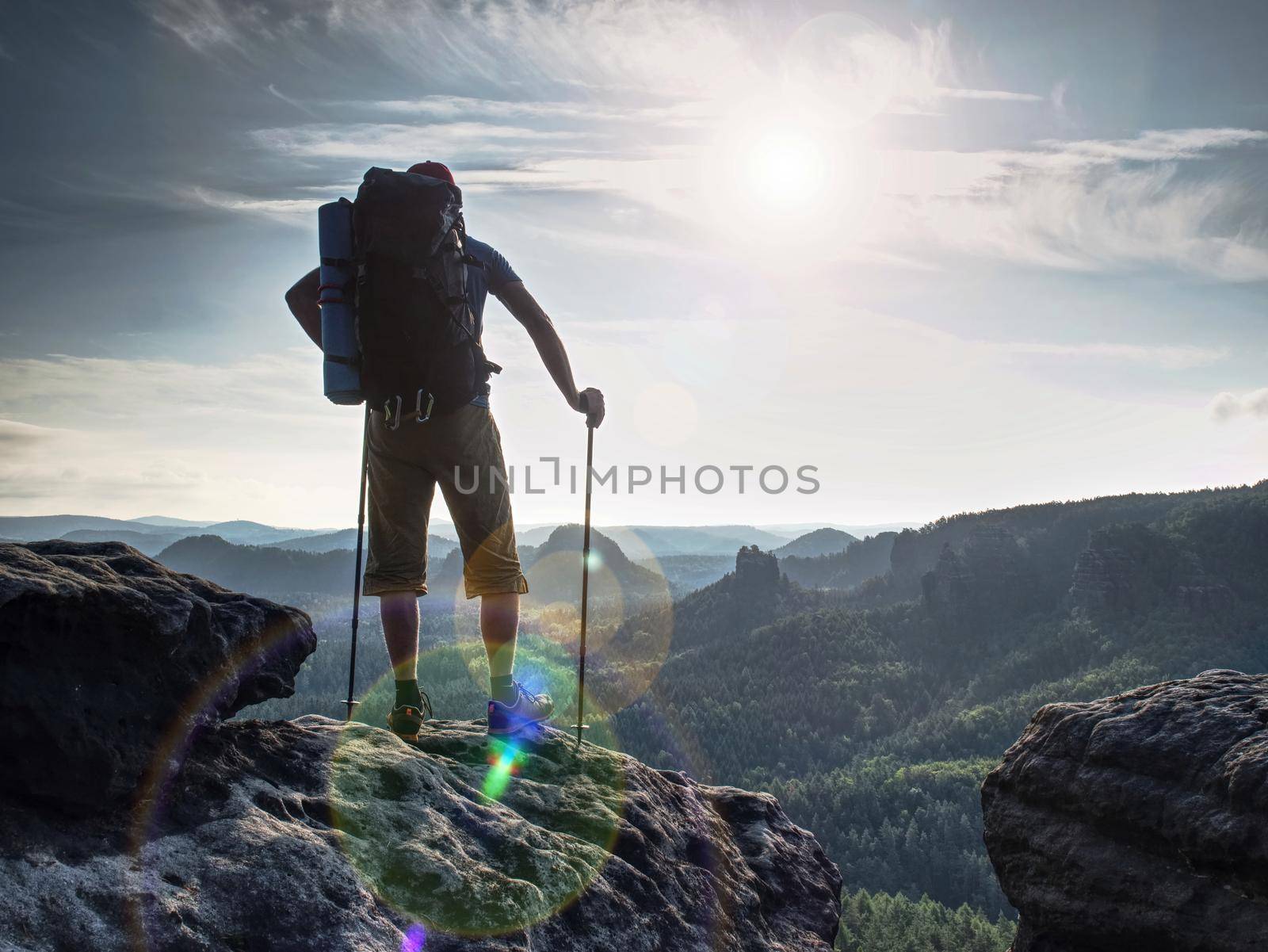 Hiker hold trekking sticks for nordic walking and deep breath at the edge.