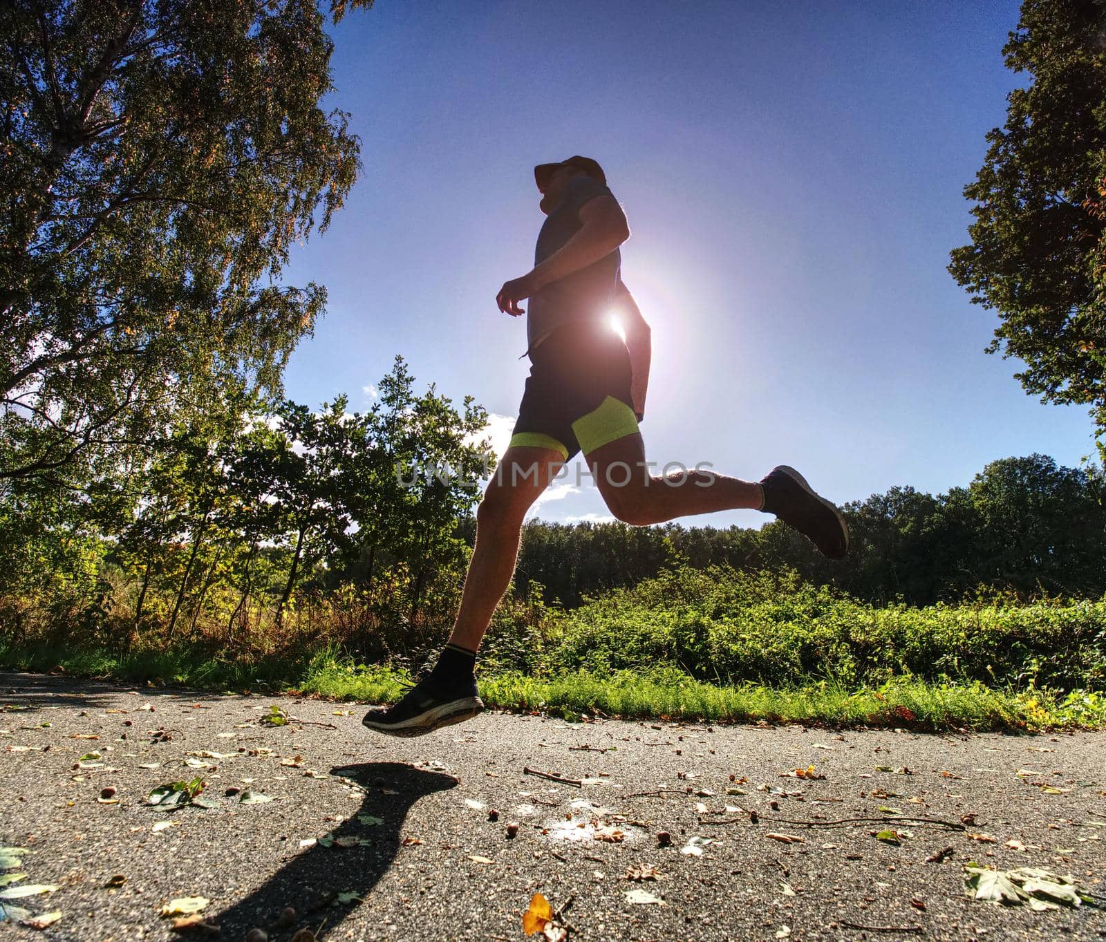 Man running quickly along country lane.  Fit and body care concept. Autumn nature.