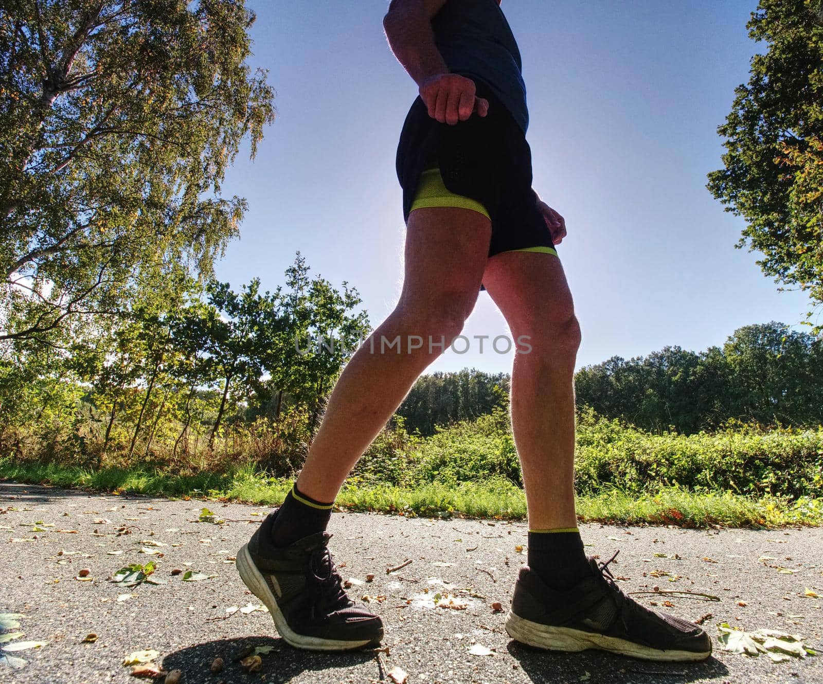 Man running quickly along country lane.  Fit and body care concept. Autumn nature.