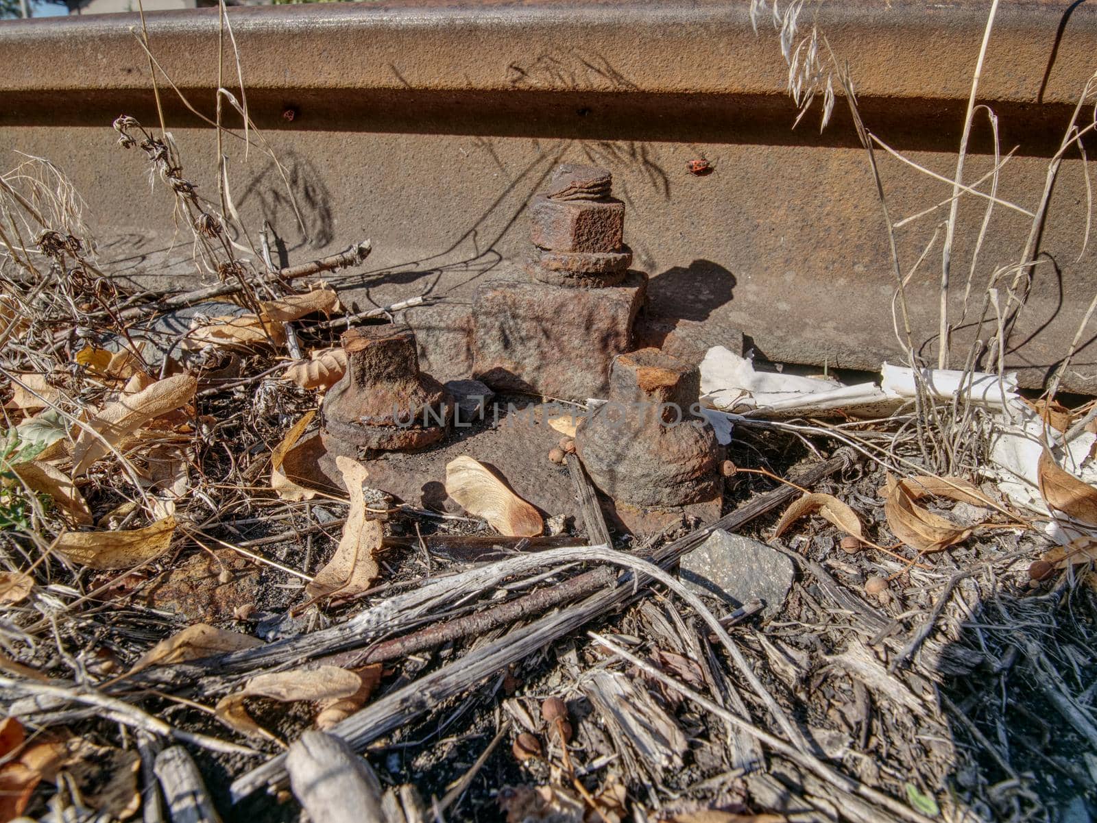 Rusty train railway detail, oiled sleepers and stones between rail way  by rdonar2