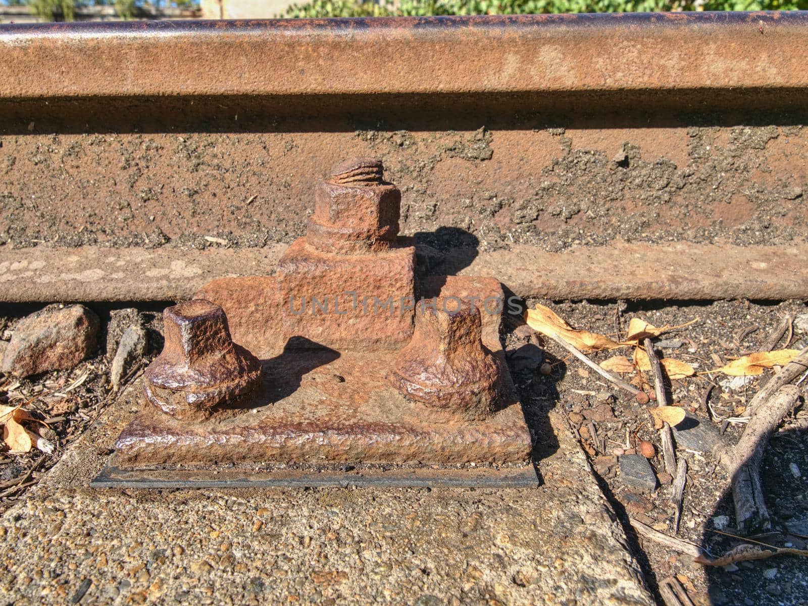 Detail of rusty screws and nut on old railroad track. Rotten wooden tie with rusty nuts and bolts. Damaged wooden railway sleeper. No train passed this railroad for a long time.