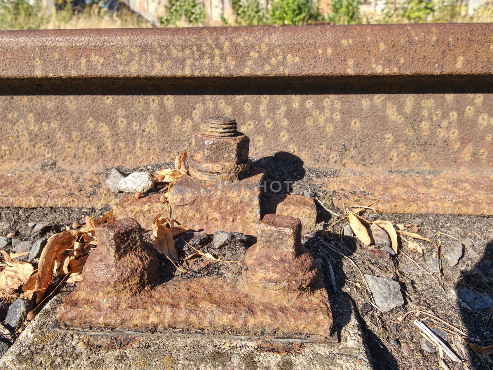 Detail of rusty screws and nut on old railroad track. Rotten tie with rusty nuts and bolts. Terrible smell extracted old wooden ties with phenol asphalt paint.