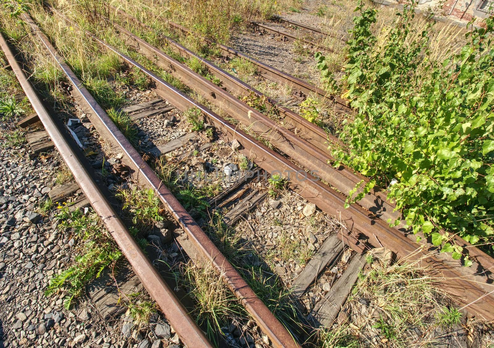 Old rusty rails in abandoned railway station. Rusty train railway detail, granite stones between rails