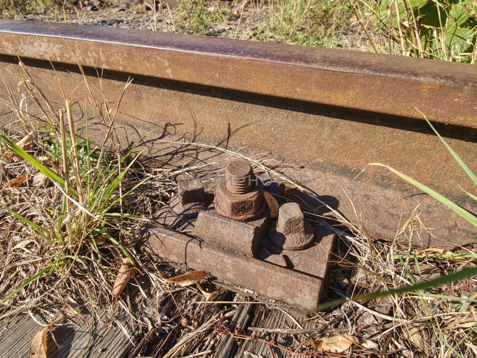 ap with nut and screw on the old rusty rail. Rusty train railway detail, oiled sleepers and stones between rail way 