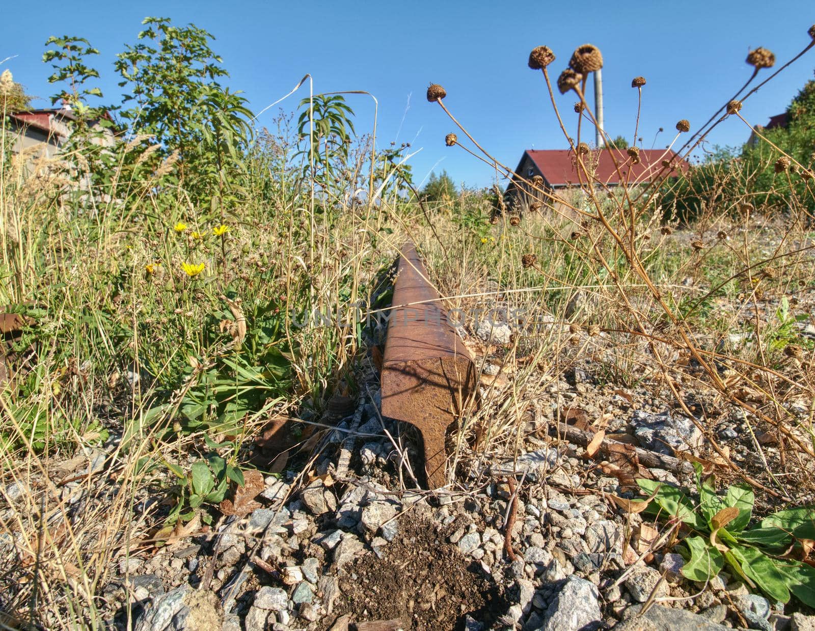 Old abandoned rail and bolt of a railway.  Rusty train railway detail, oiled sleepers and stones between rail way 