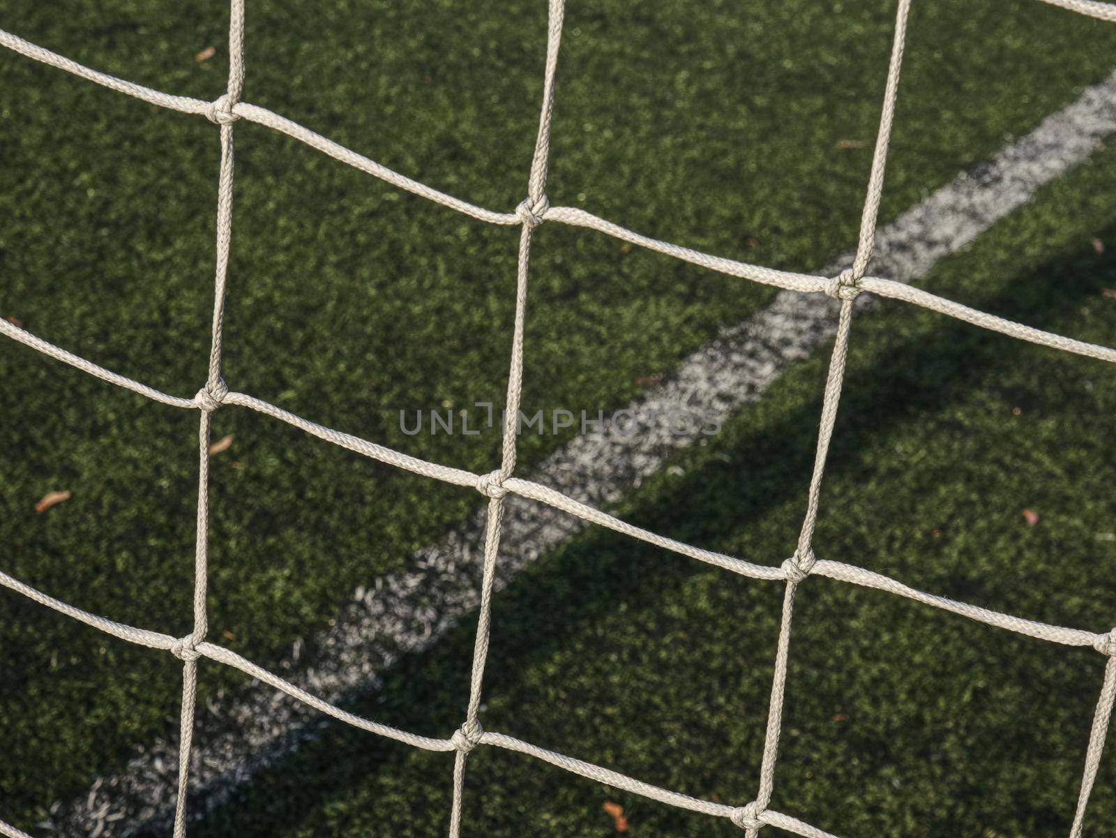 Frame of football gate, white gate net on background of a green football field