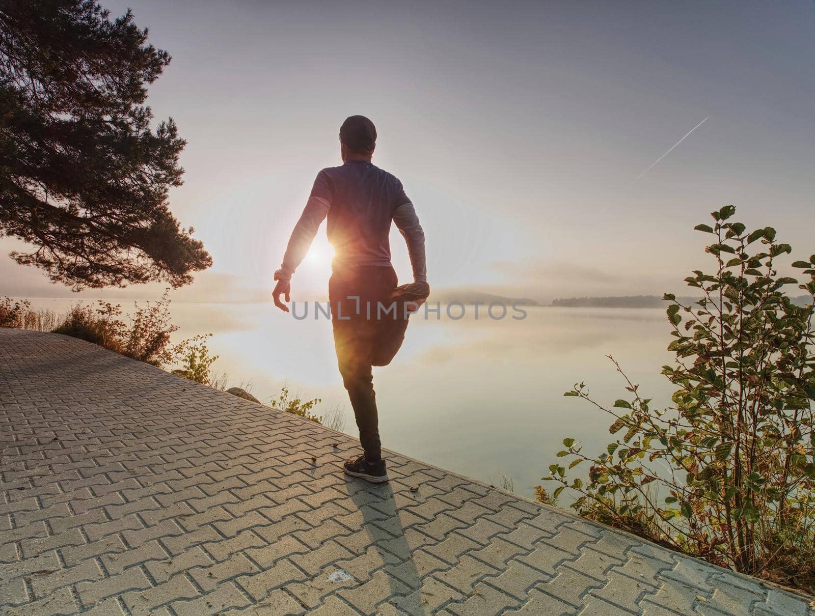 Athletic sport man stretching leg muscles before run by rdonar2