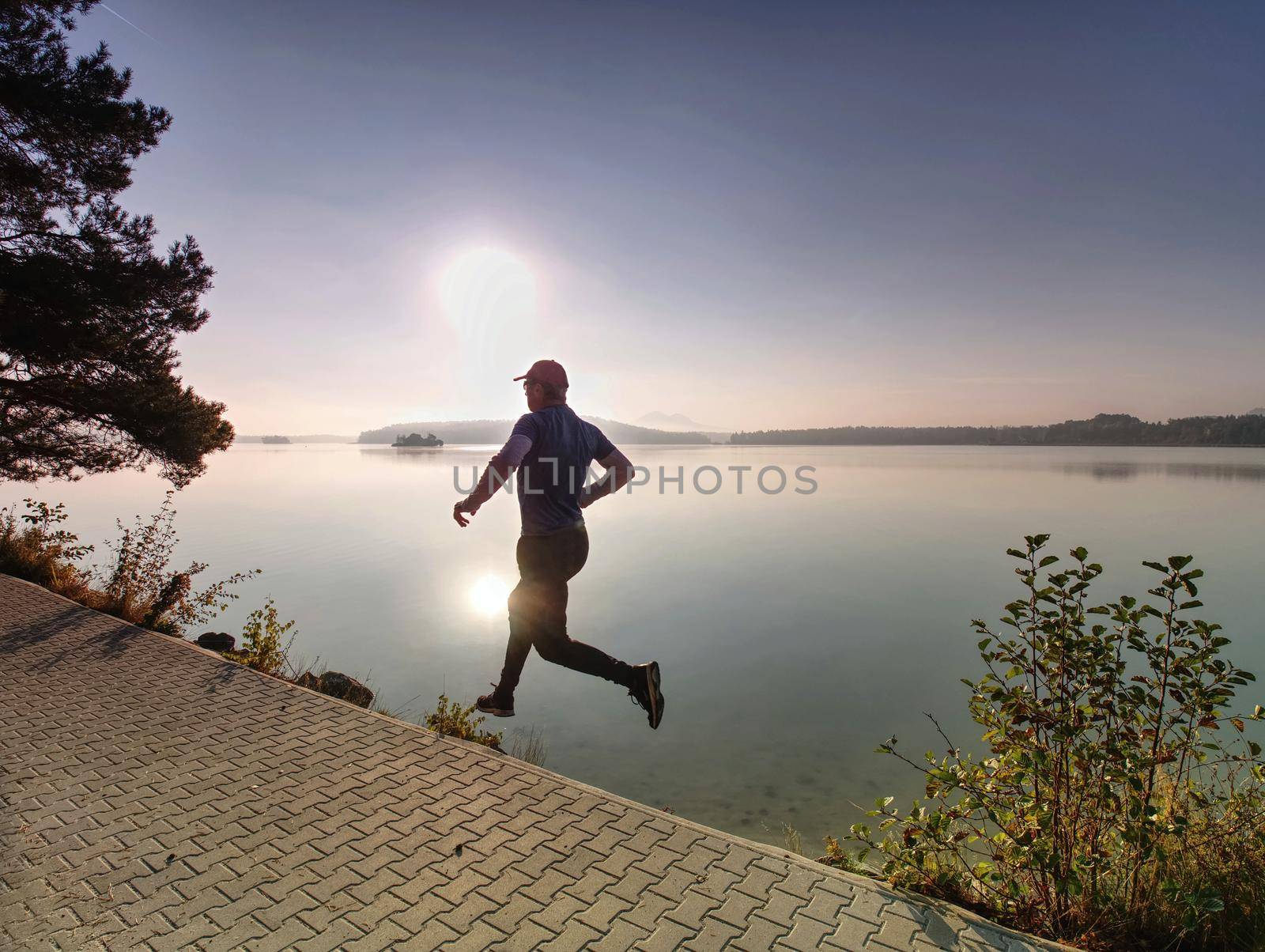 Silhouette of athlete run on sunset background copy space. Man with sportive figure practices sport running for life. Sport and training concept.