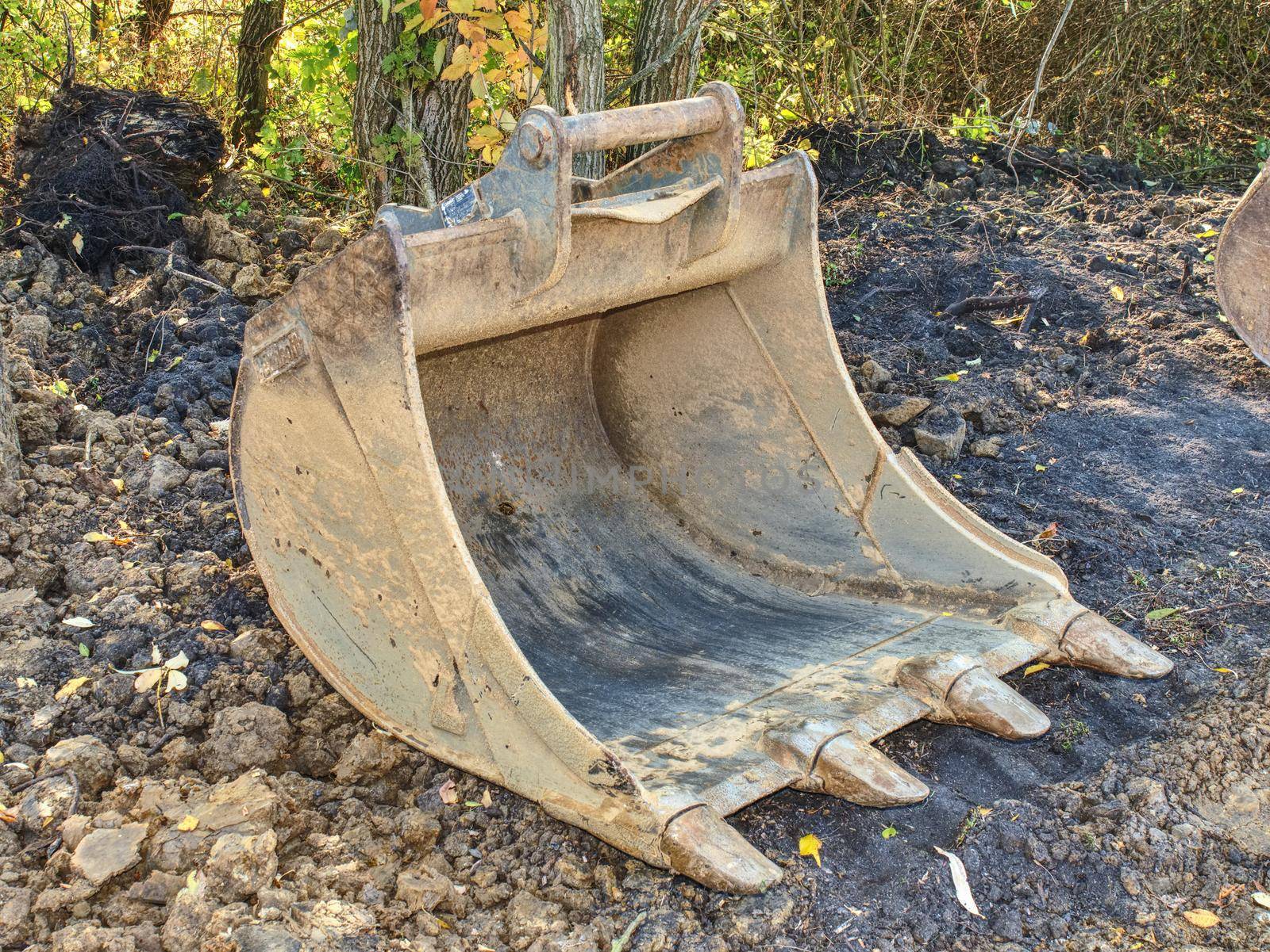 Shovel of digger at trench for pipelines. Construction works at town.