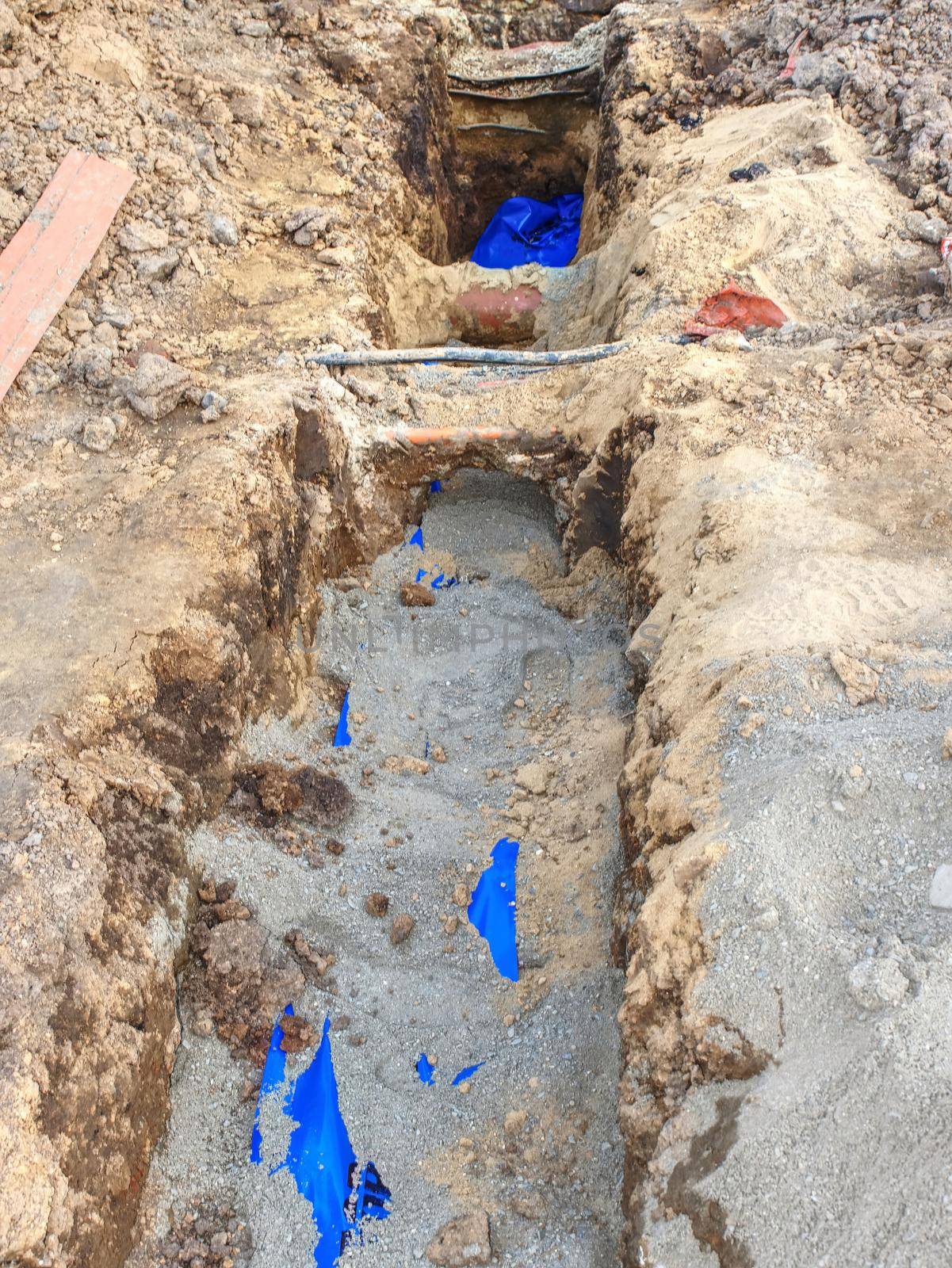 Open trench under pavement with hidden water pipes, electrical and internet wires, gas tubes and others utilities.