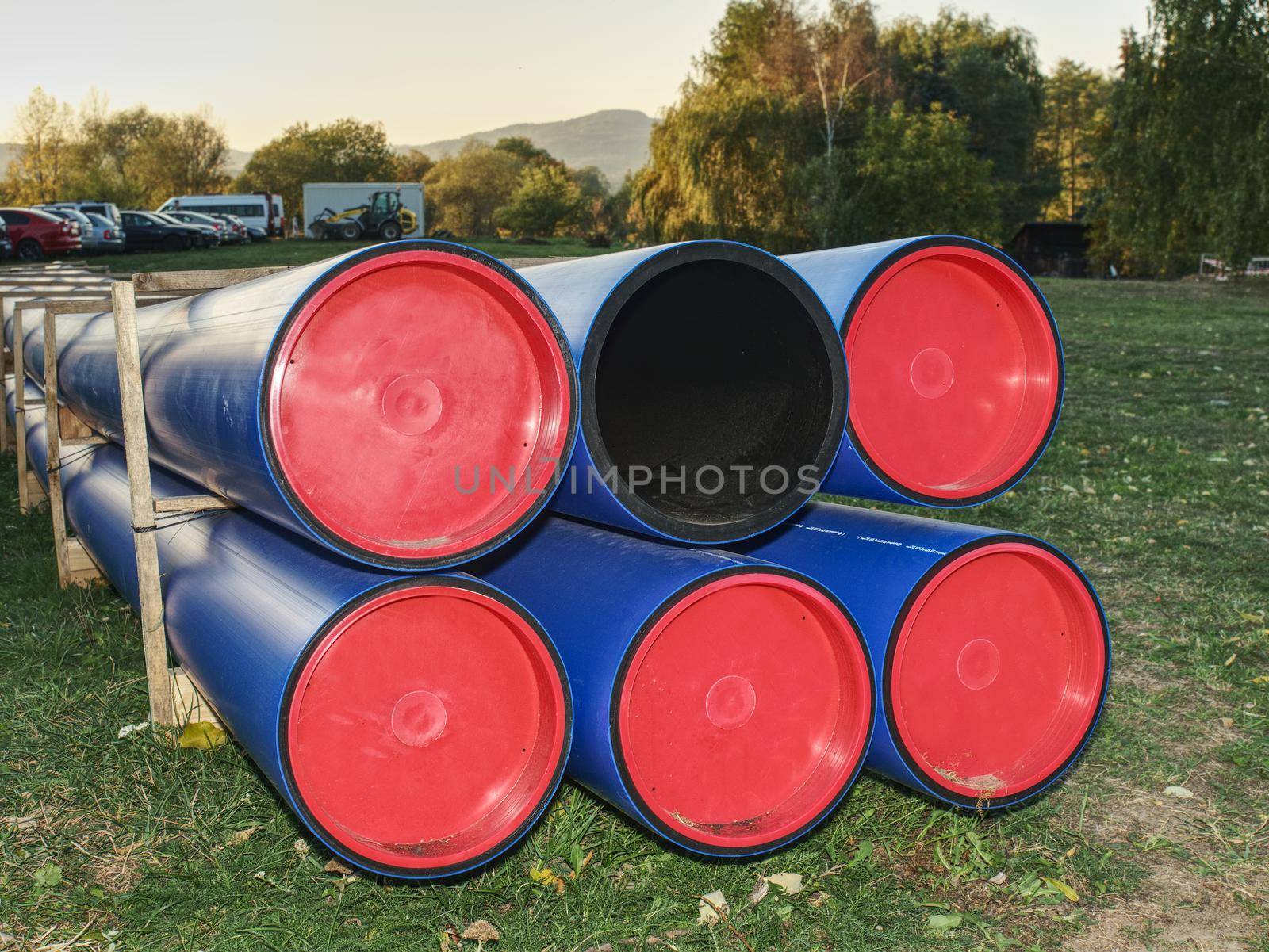 HDPE pipe for water supply stacked at building site  on ground under the open sky.  New branch of portable water for city. Construction site with machinery