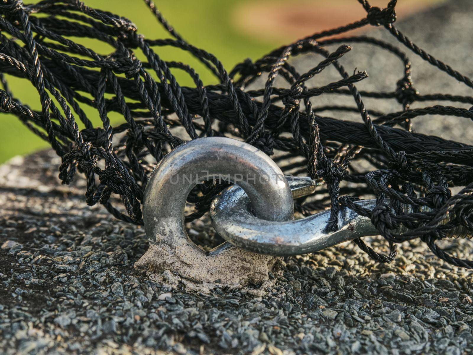 Steel twisted rope and steel bolt anchor eye in concrete base. The end knot of steel rope. 