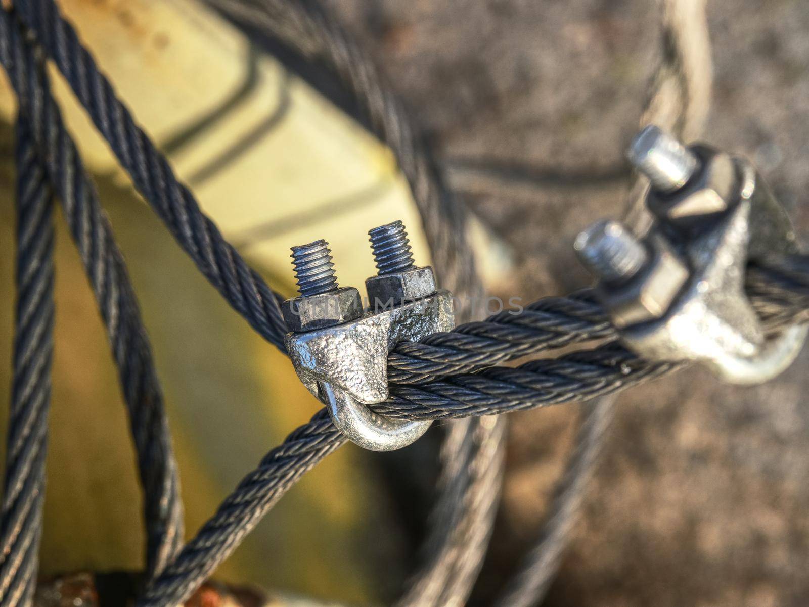 The end knot of steel rope. Stainless steel turnbuckle and sling steel in base. Detail of steel bolt anchor eye in ground
