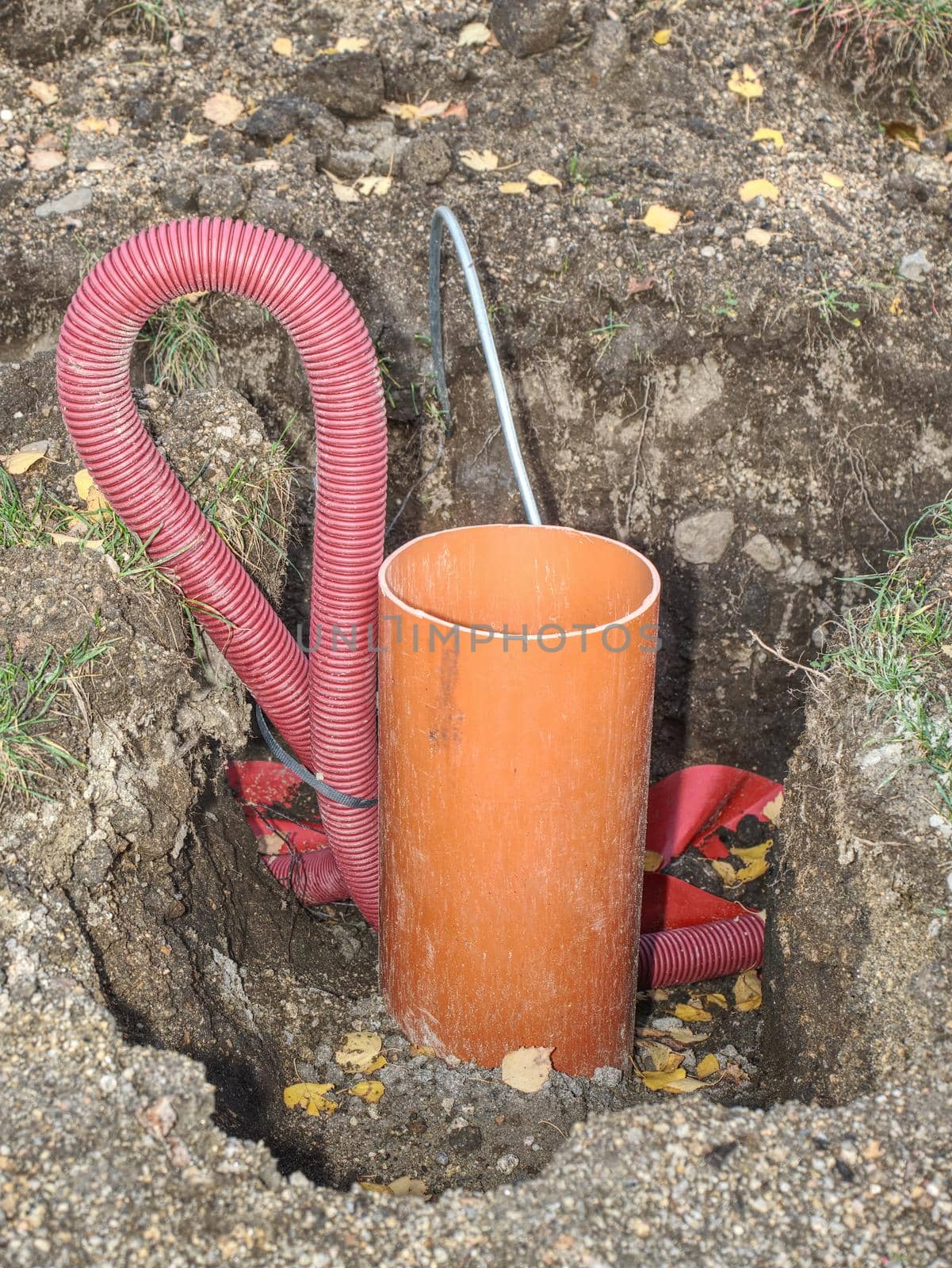 Ribbed red plastic pipes containing electric cables, repair work in the park