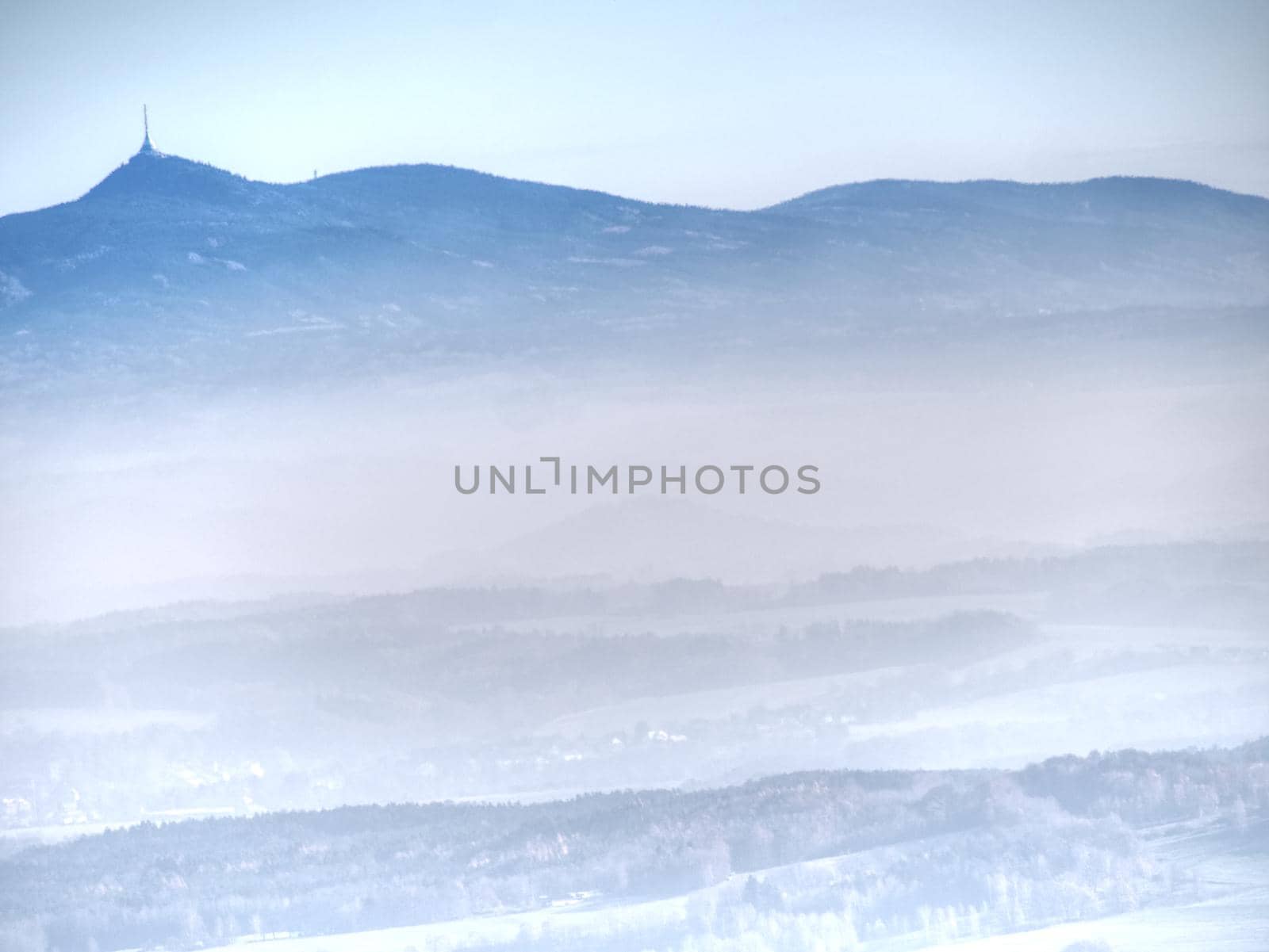 Blue mist above rounded hills in Landscape. Outline of real landscape in morning golden light.