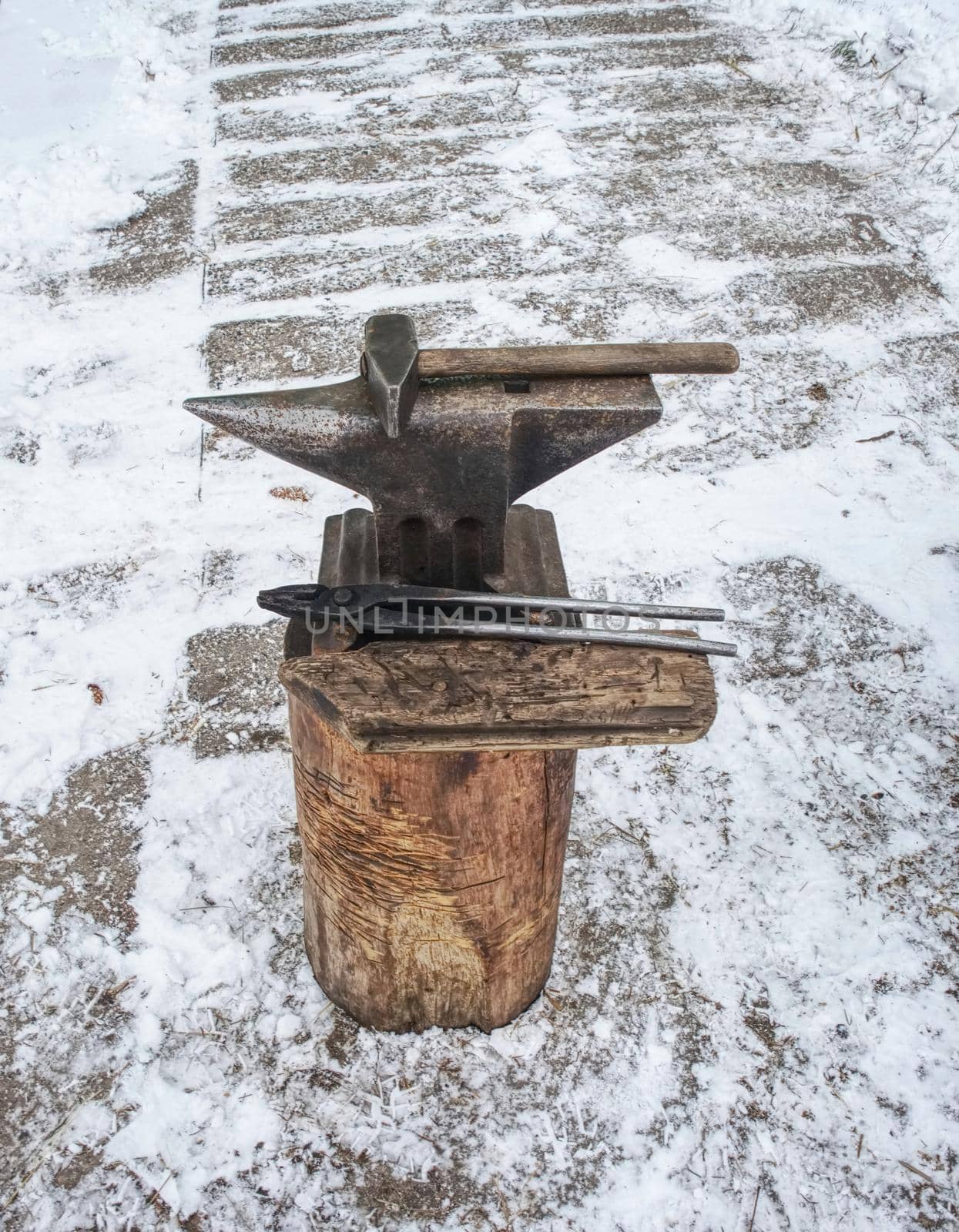 Hammer lies on the anvil, the blacksmith work place in horse farm. Winter morning with snow cover.
