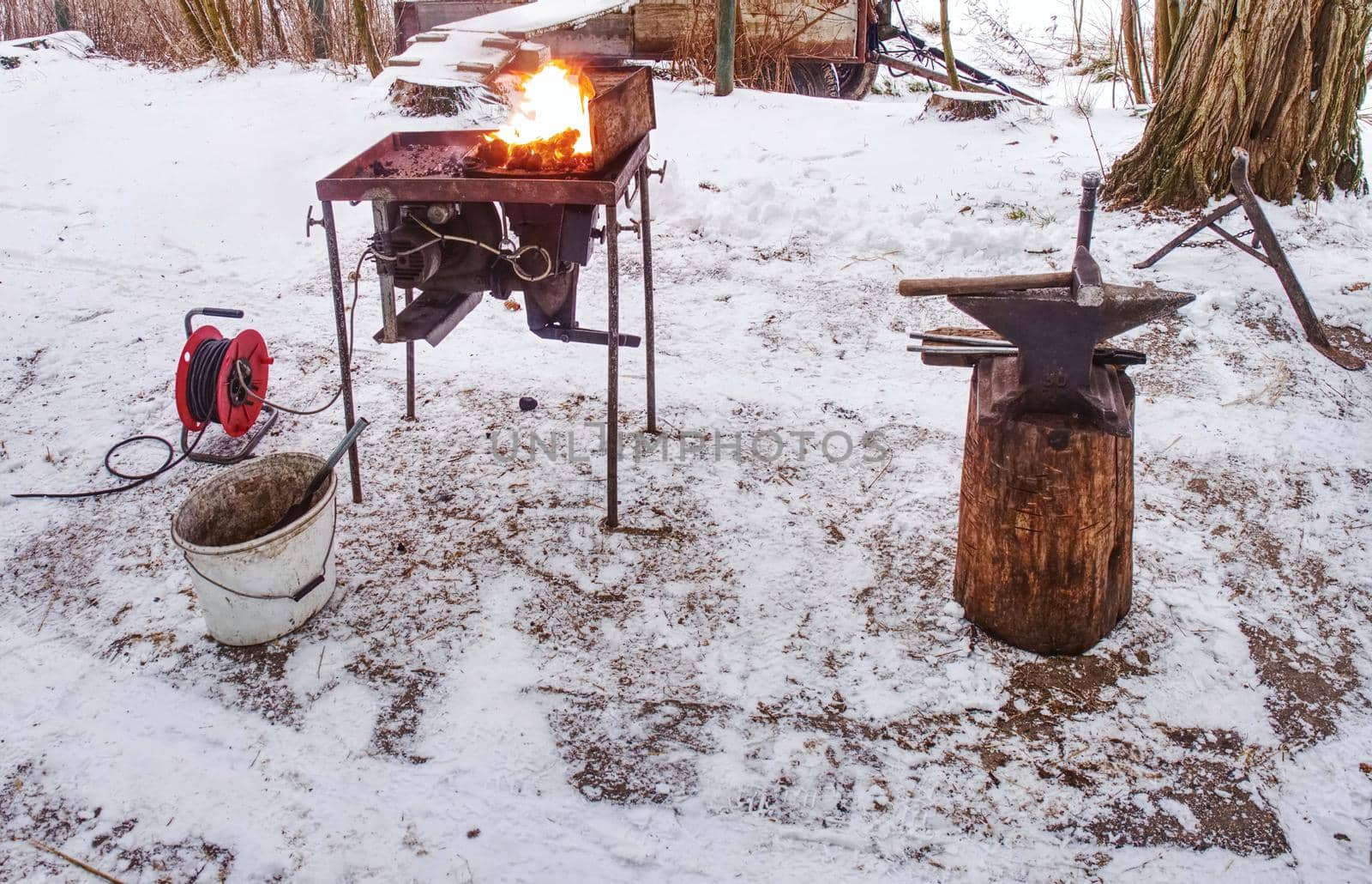 Small mobile blacksmith's forge with horse hoof inside for heating. Daily routines in horse farm.