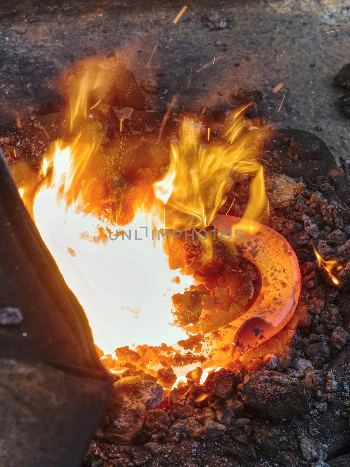 Craftsman blacksmith warming iron to create  horseshoe in the fire and on the anvil