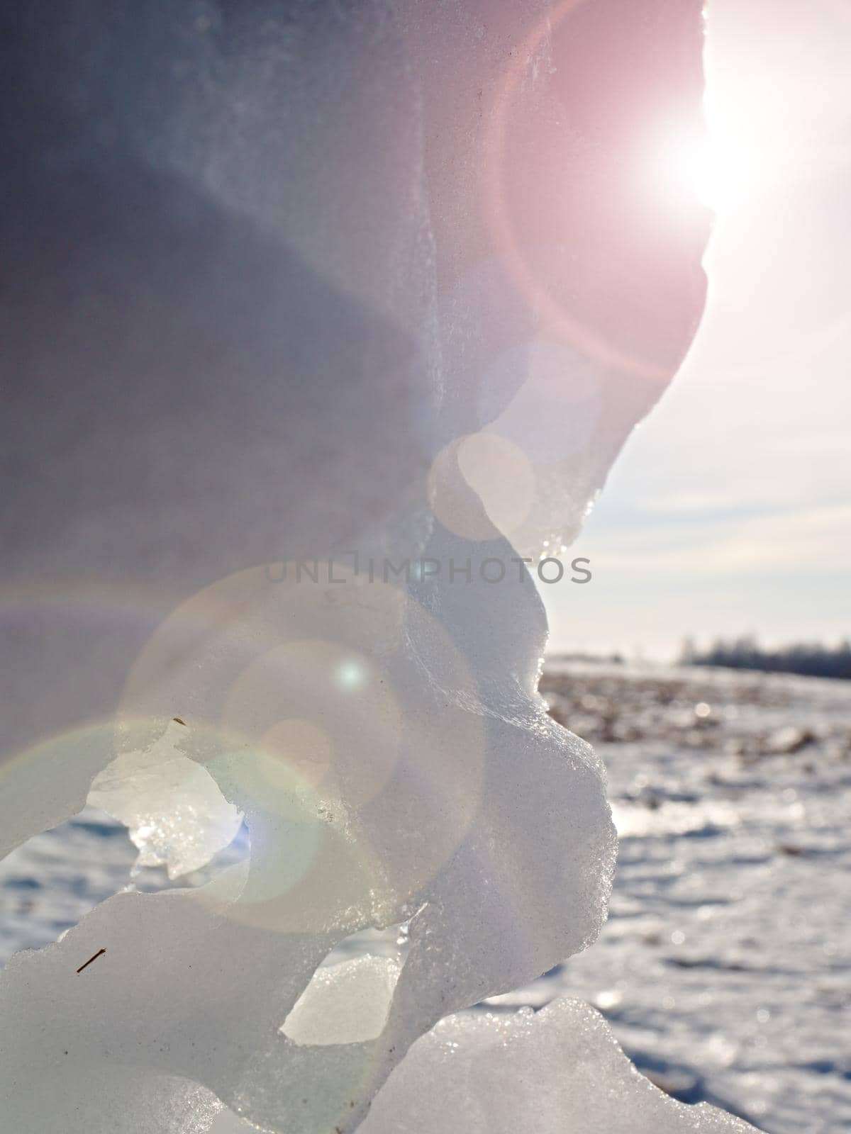 Hole in icy snow with sun flares. Lovely winter scene.