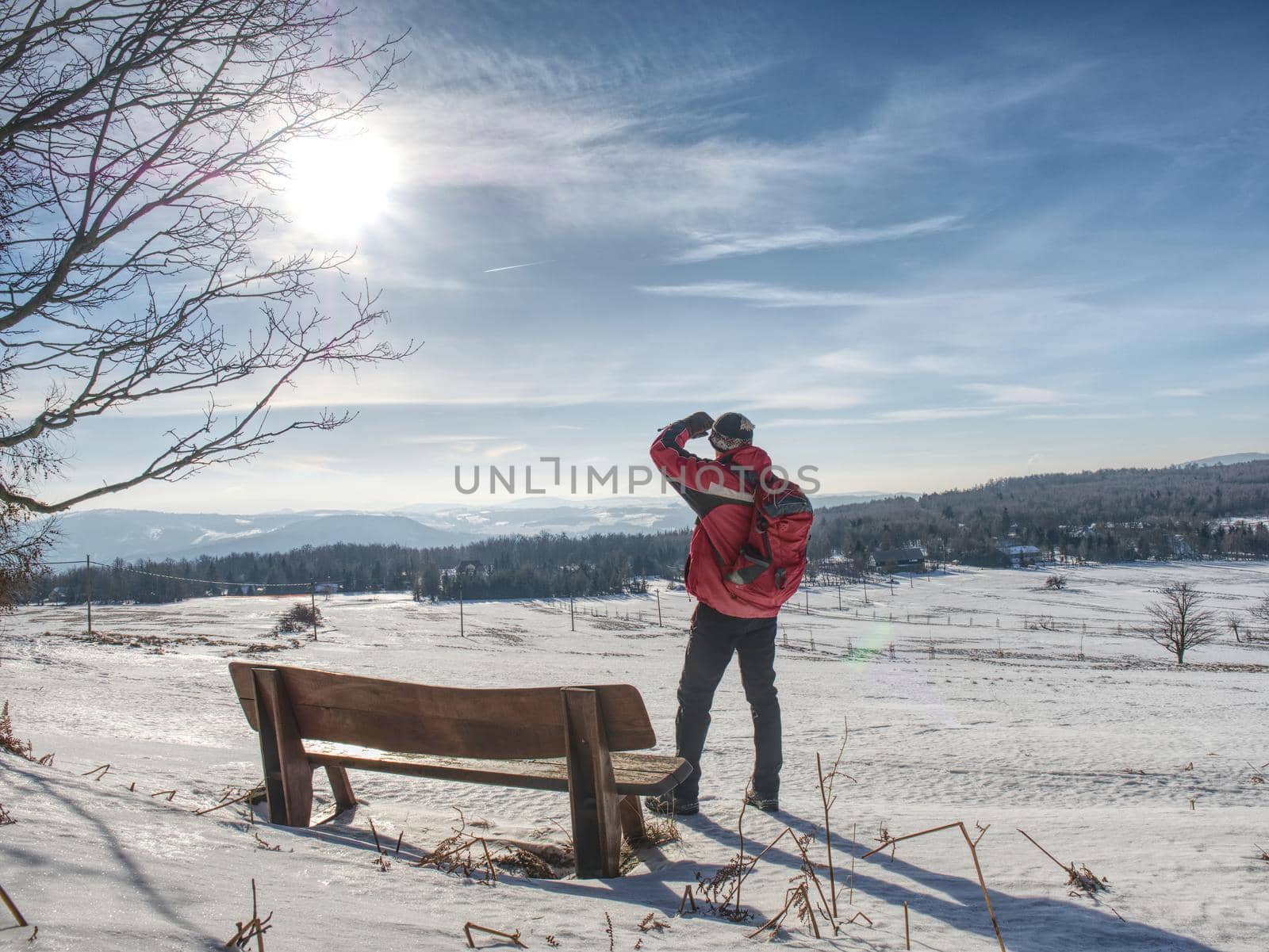 Back view of man hiker with backpack looking to landscape covered snow