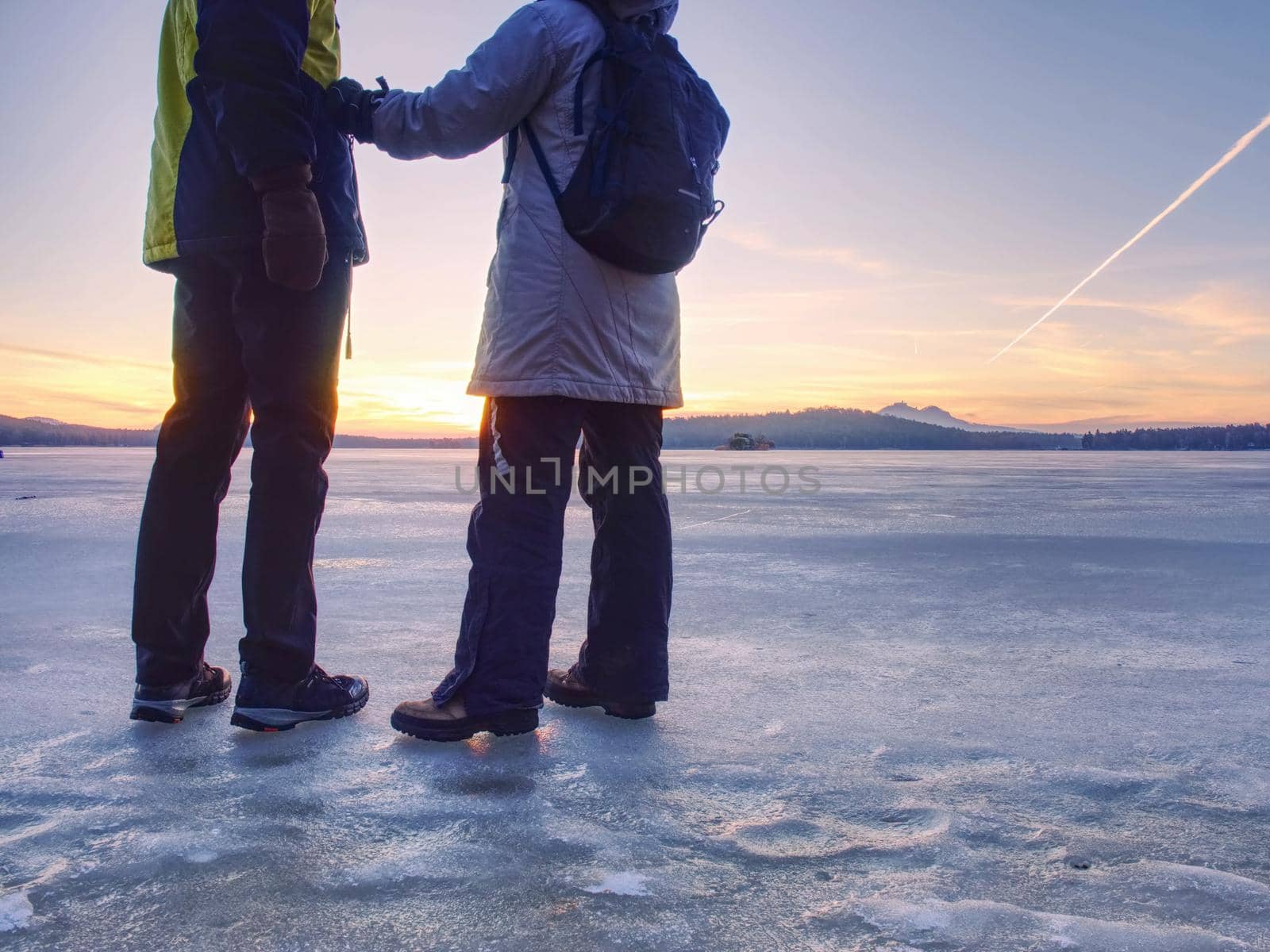 Couple, man and woman walking on ice on a frozen lake by rdonar2