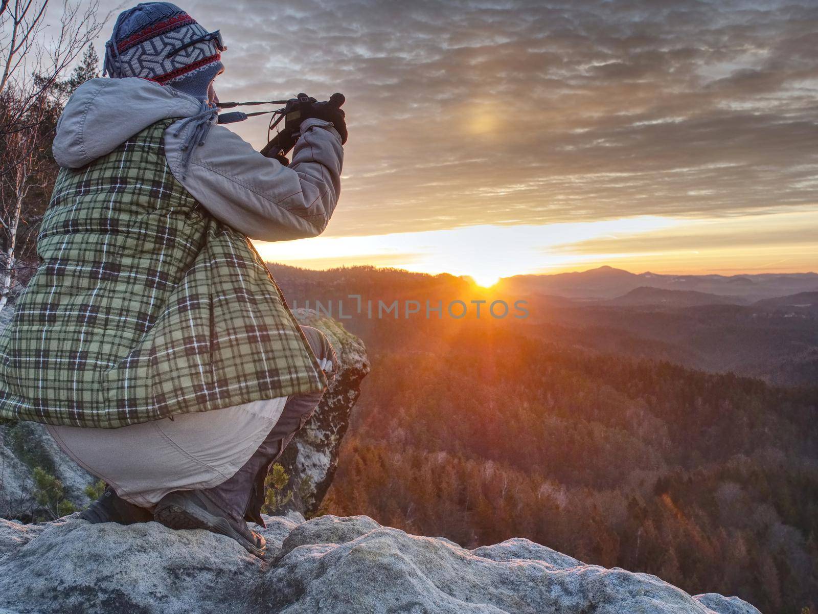Hiker woman photographer takes impresive photos from sharp cliff edge.