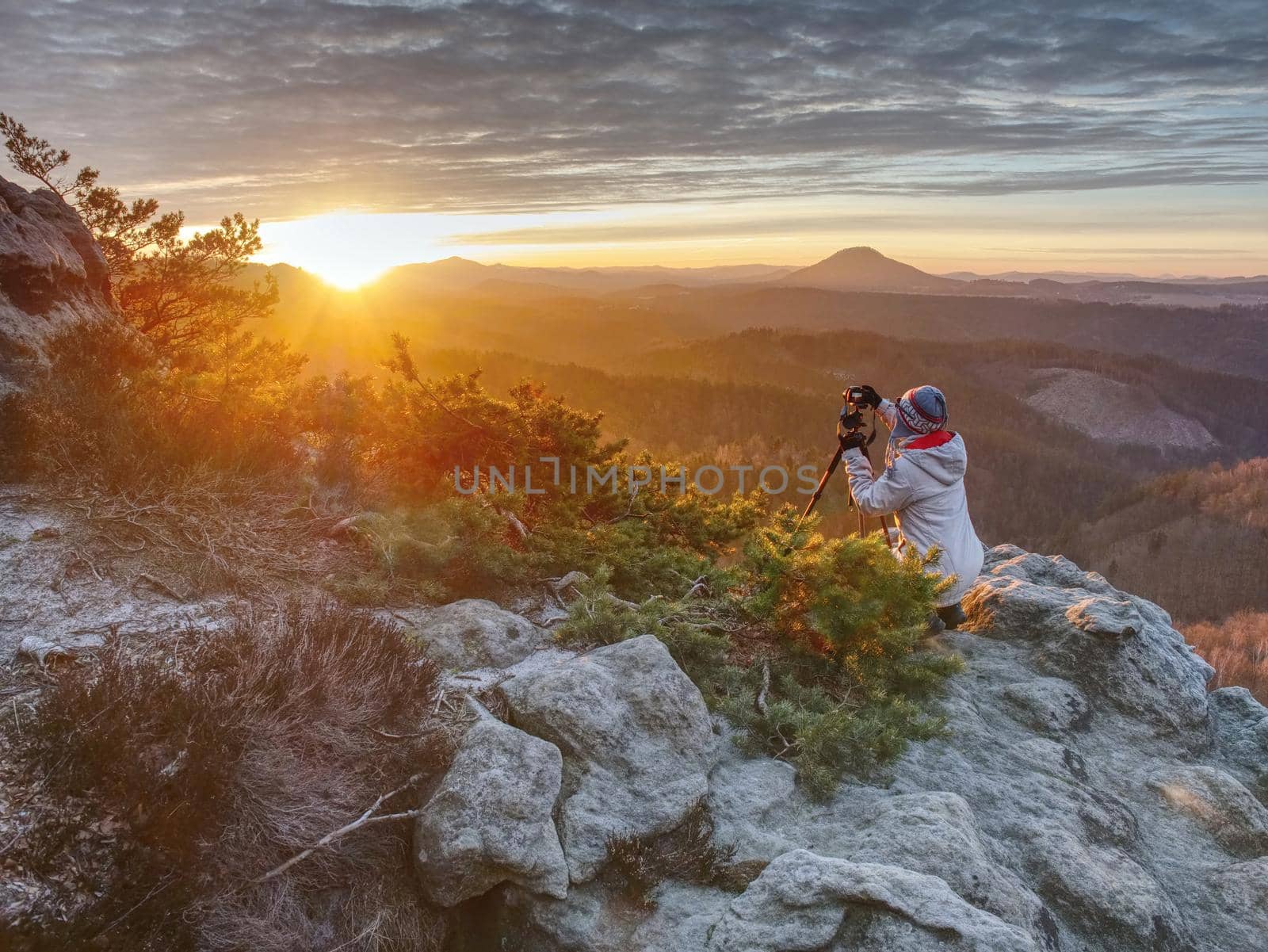 Woman hiker set tripod with camera on exposed rocky summit by rdonar2