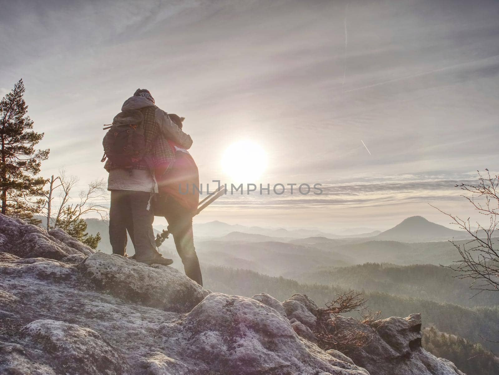 Man photographer and woman traveler  photographing with the camera on the tripod. Two people  takes a shot of the mist covered mountains and the rocks 