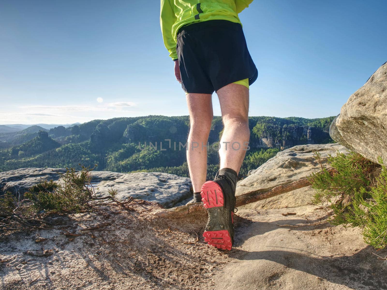 Runner workout outdoor in rocks  during trail marathon on mountain path. Sunny flares on amazing nature