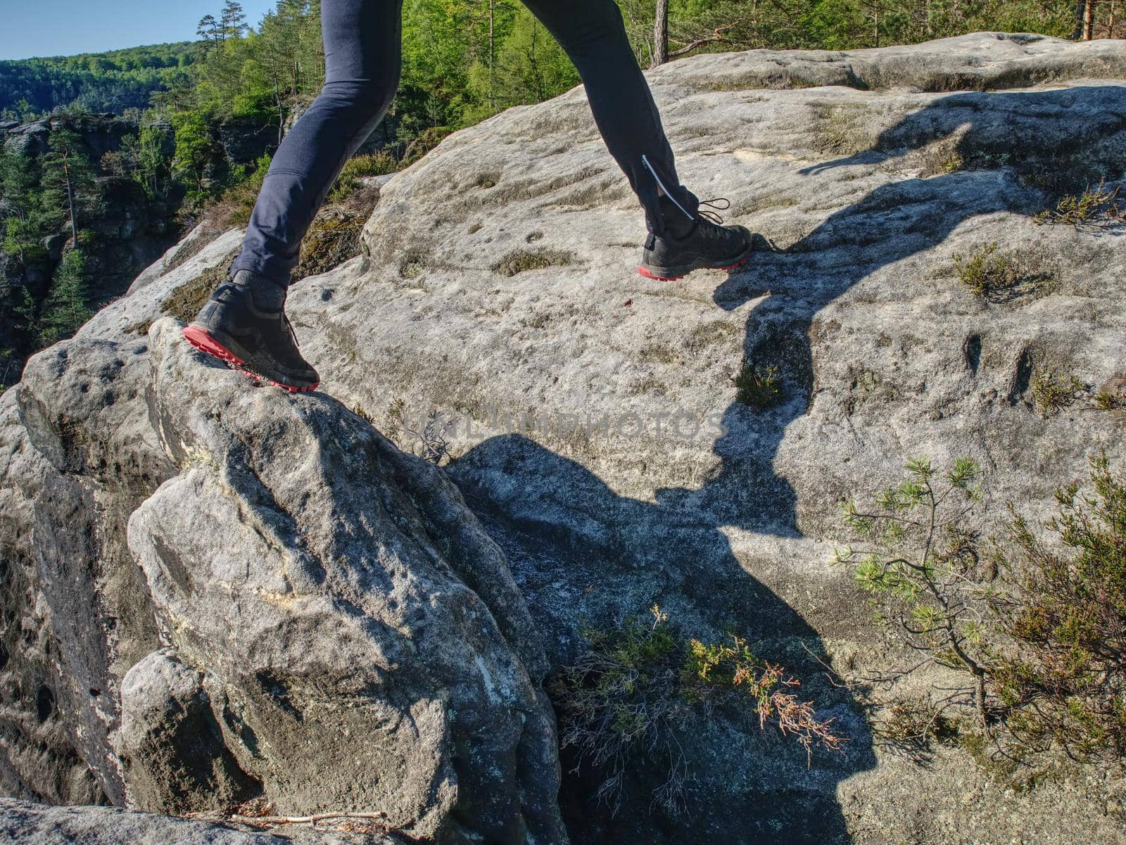 Fitness man trail runner running to rocky mountain top on cracked rocky block.