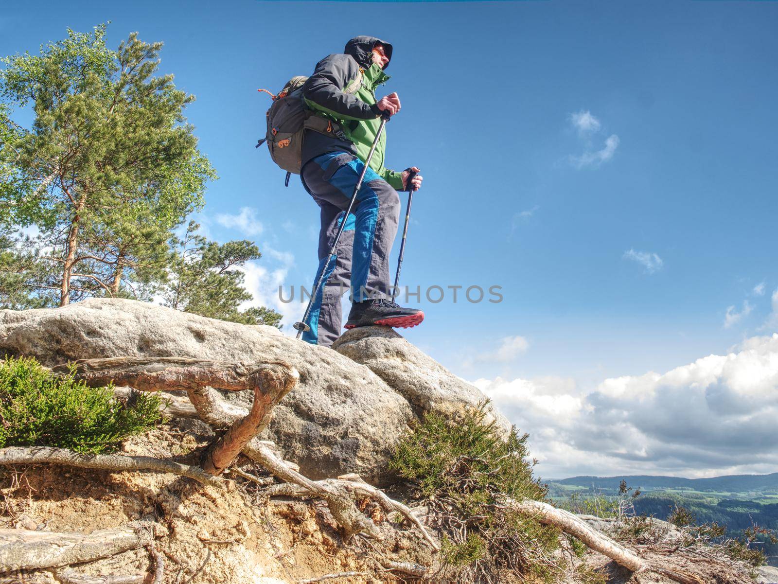 Traveler in the mountains stands on a rock, leaning on trekking sticks. Mountain, landscape.