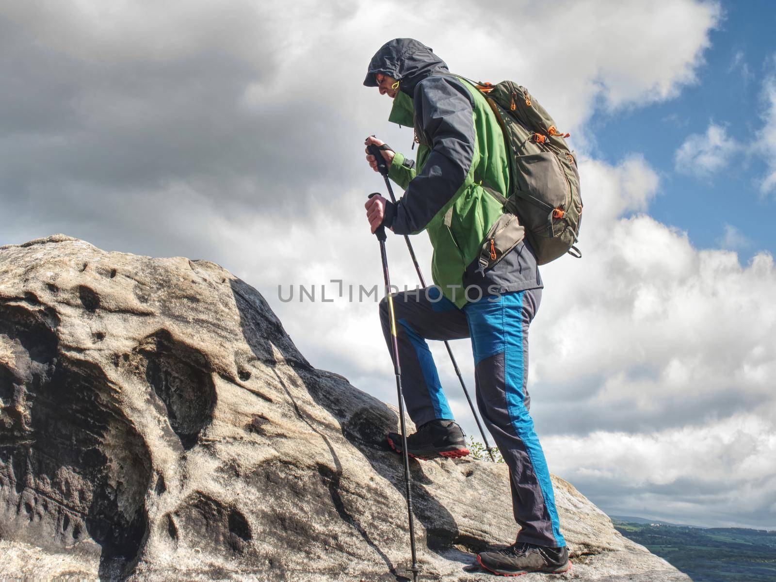 Man backpacker climbing over sandstone bolder high up on a mountain hike