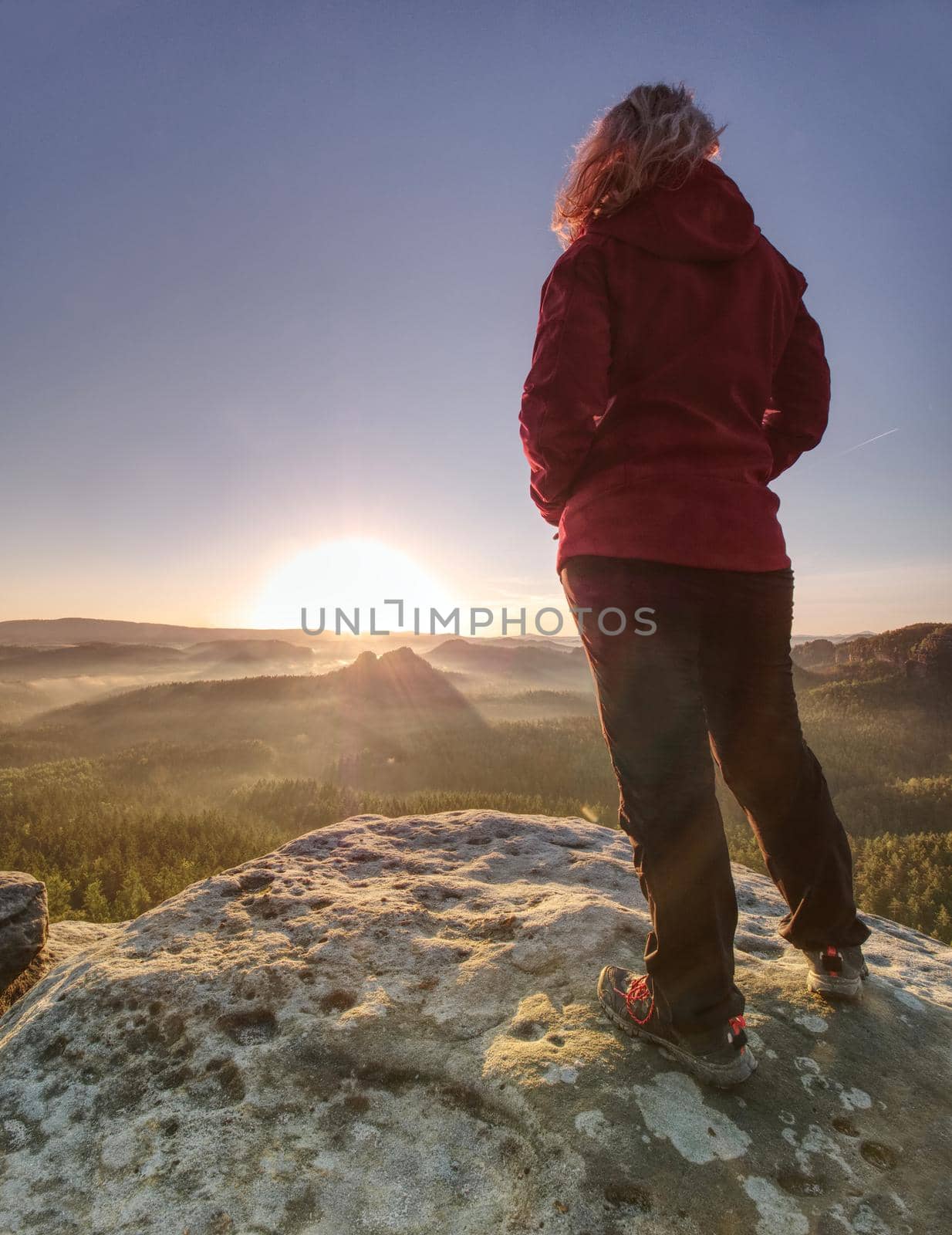 Blond girl traveler with hands in jacket pockets hiking in mountains.  Travel Lifestyle concept. Summer vacations outdoor 
