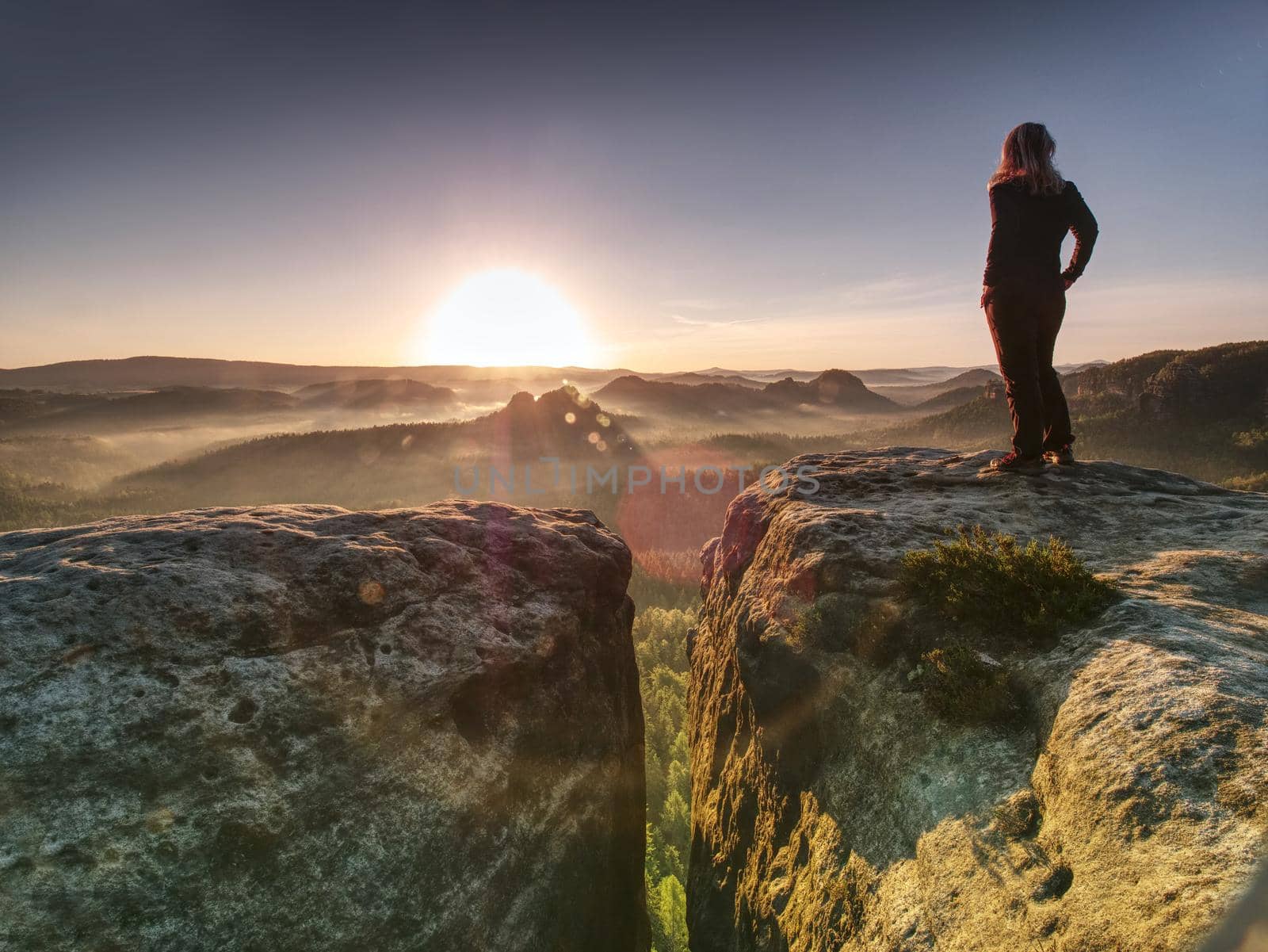 Alone woman hiker model in wild nature within marvelous sunrise. Misty valley somewhere in hilly ladscape.