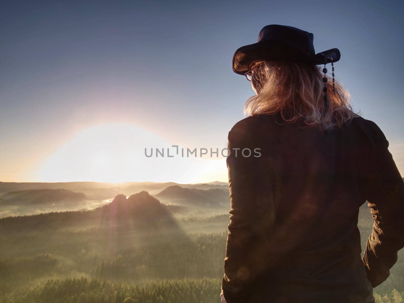 Fit body blond hair woman on the top of the high rocky mountain in the evening. Beautiful sunset autumn forests rocks and hills on the background