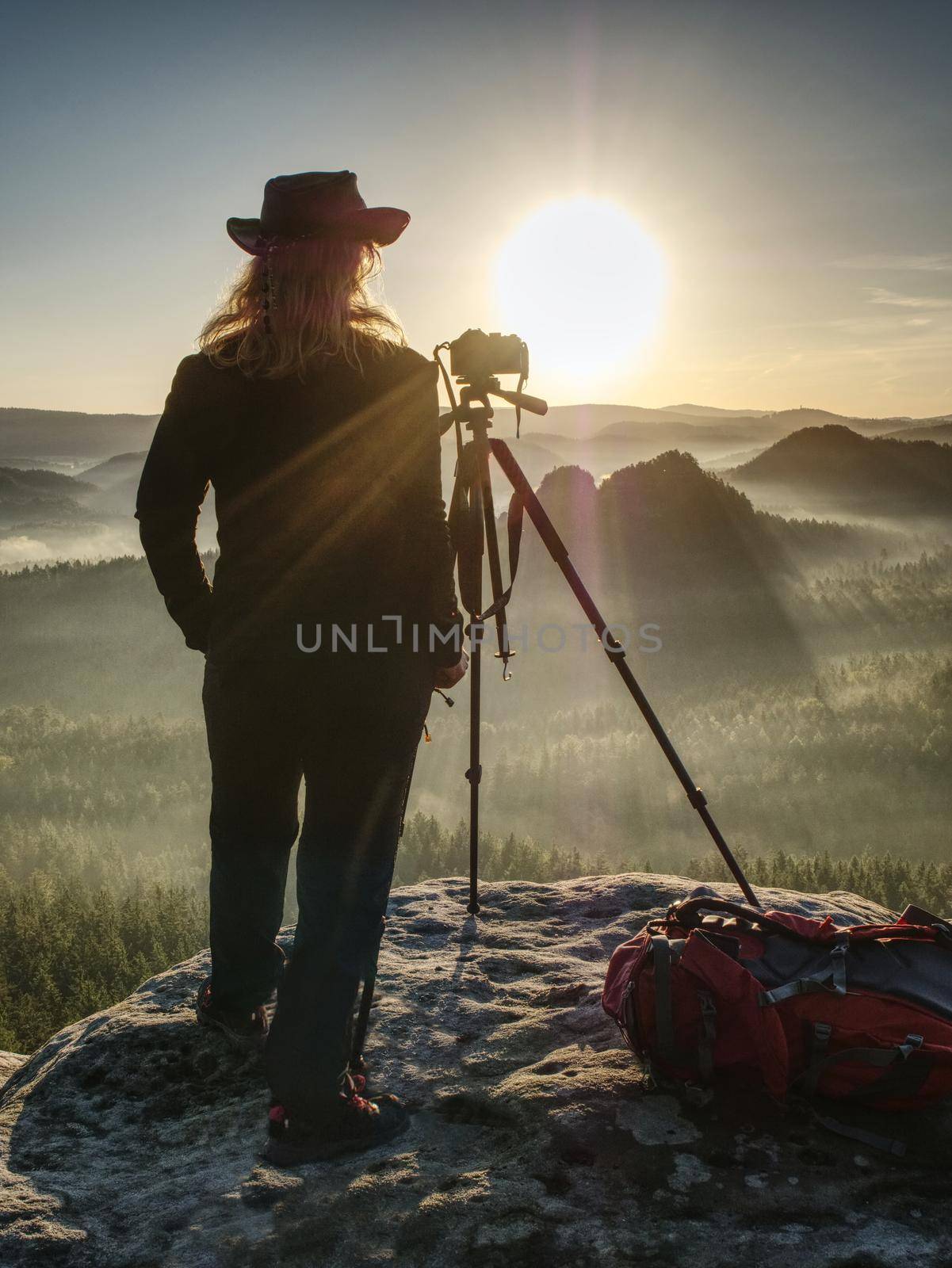 Nice girl photographer in cowboy cap photographing on her digital mirror camera. Journey landscape vacation concept, wind mountain