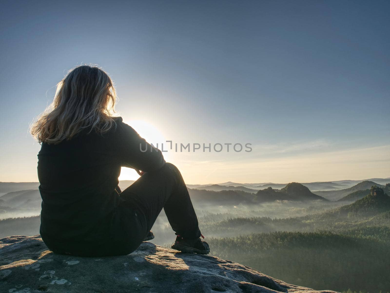 Peaceful landscape. pretty girl sit on rocks, look far away by rdonar2