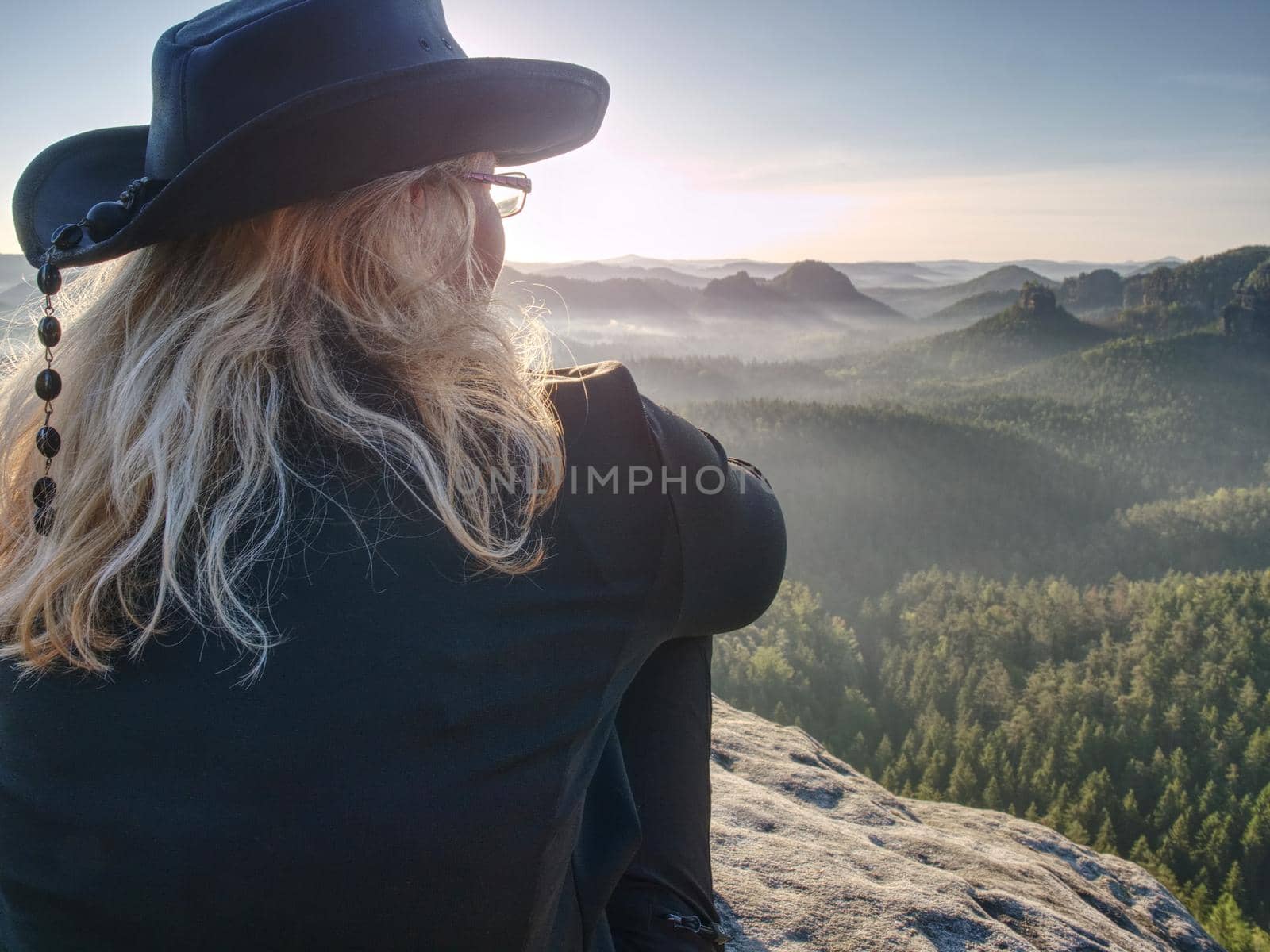 Woman hiker with leather hat conquer highest peak. Woman hiker traveling alone in nature. Mountain landscape. . Hipster hiker style.