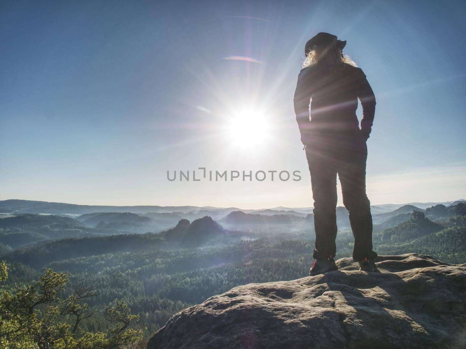 Hiker girl with leather cap stay with hands in pocket on cliff  by rdonar2