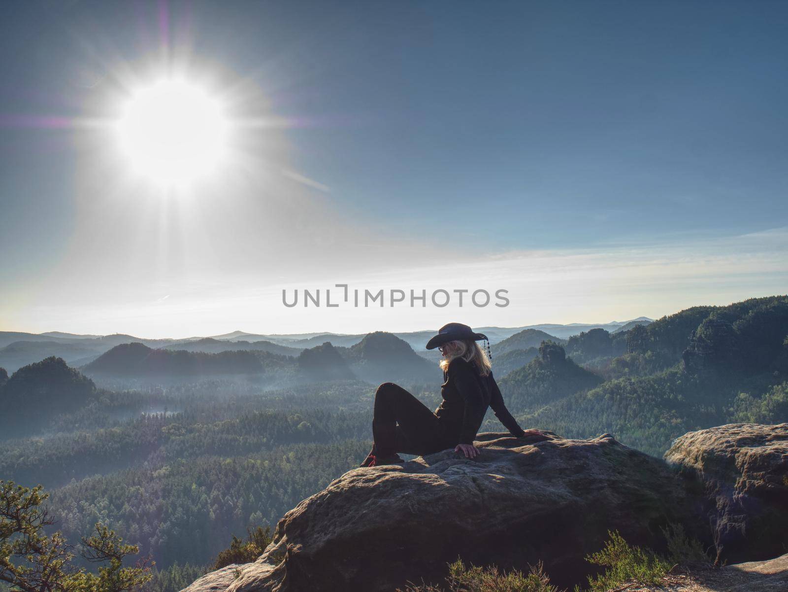 Rocky mountains with blond girl in a cowboy style. Sharp viewpoint above large valley