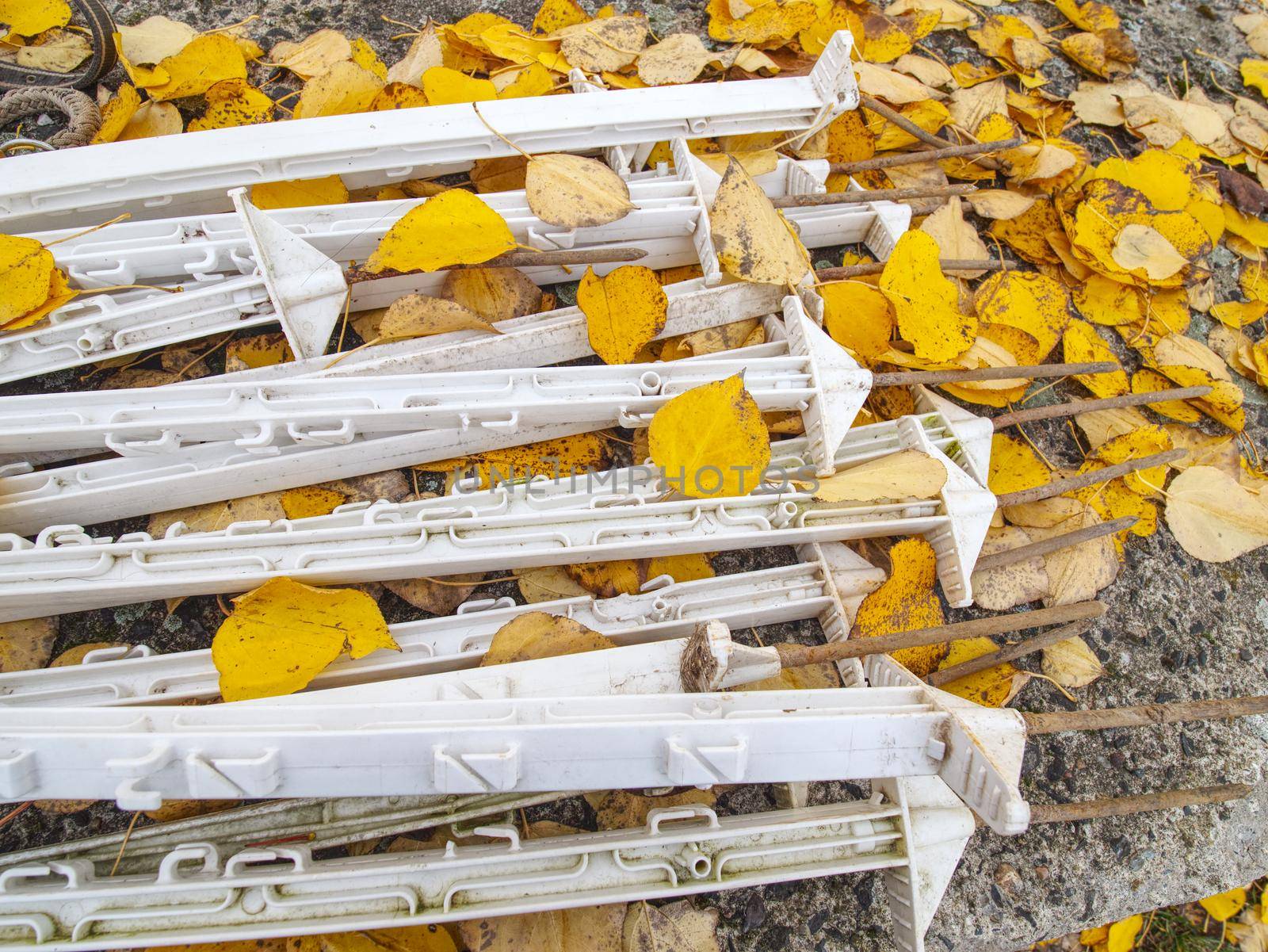 Plastic poles ready for building electric fence around paddock.  Poles stacked in yellow poplar leaves on ground