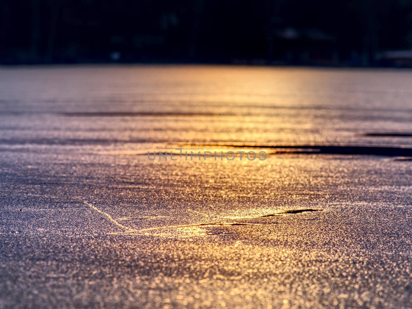 Water and ice edge. Ice with purple brilliant color covered the dark water in bay. Blue orange ice on a freezing lake