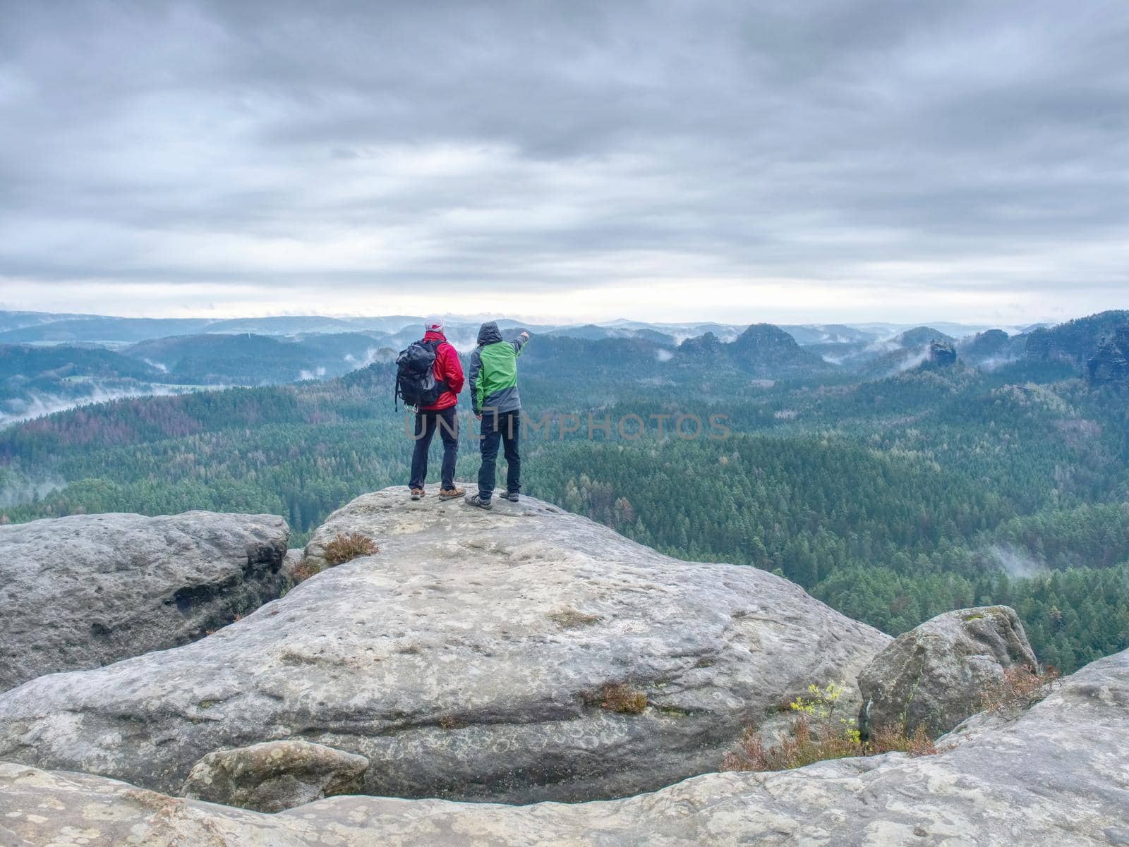 Tourist couple on the top of rocky mountain. Friends in nature.